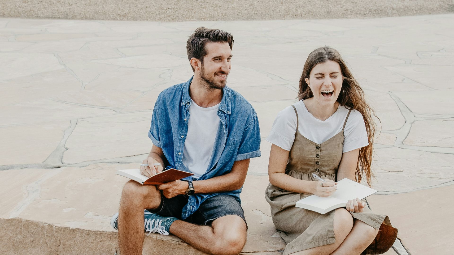 man and woman sitting side by side holding notebooks