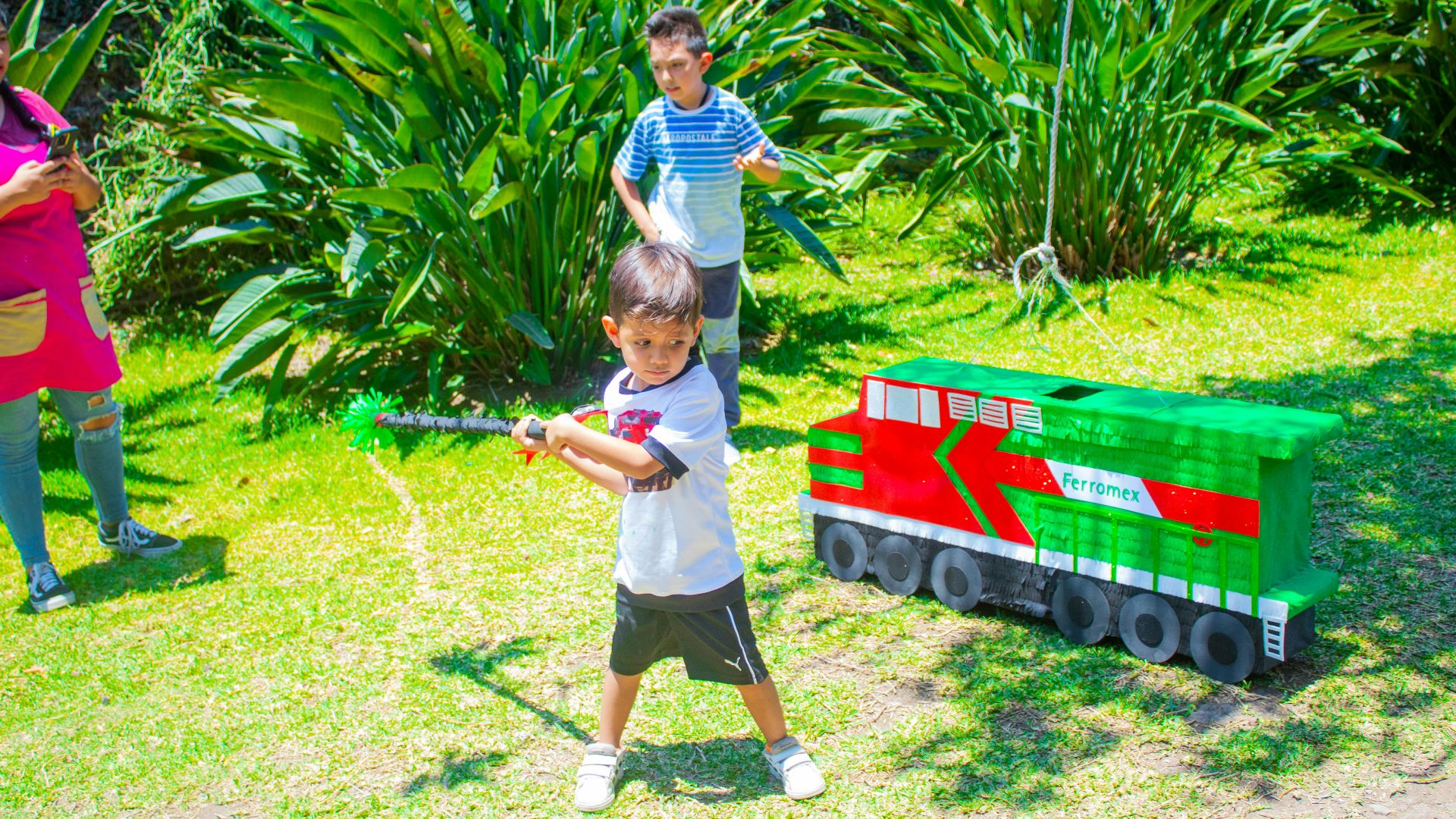 a young boy holding a baseball bat next to a toy train