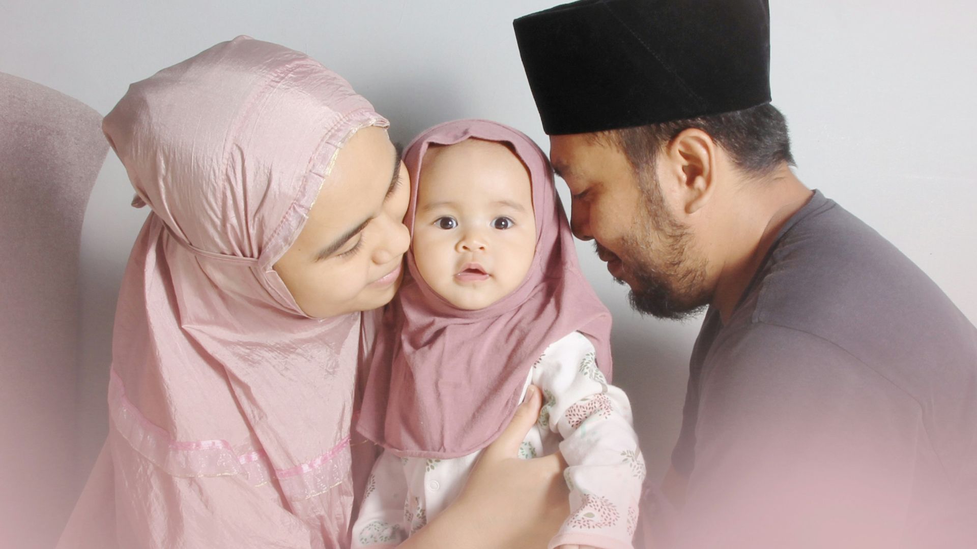 man in brown dress shirt carrying baby in white onesie