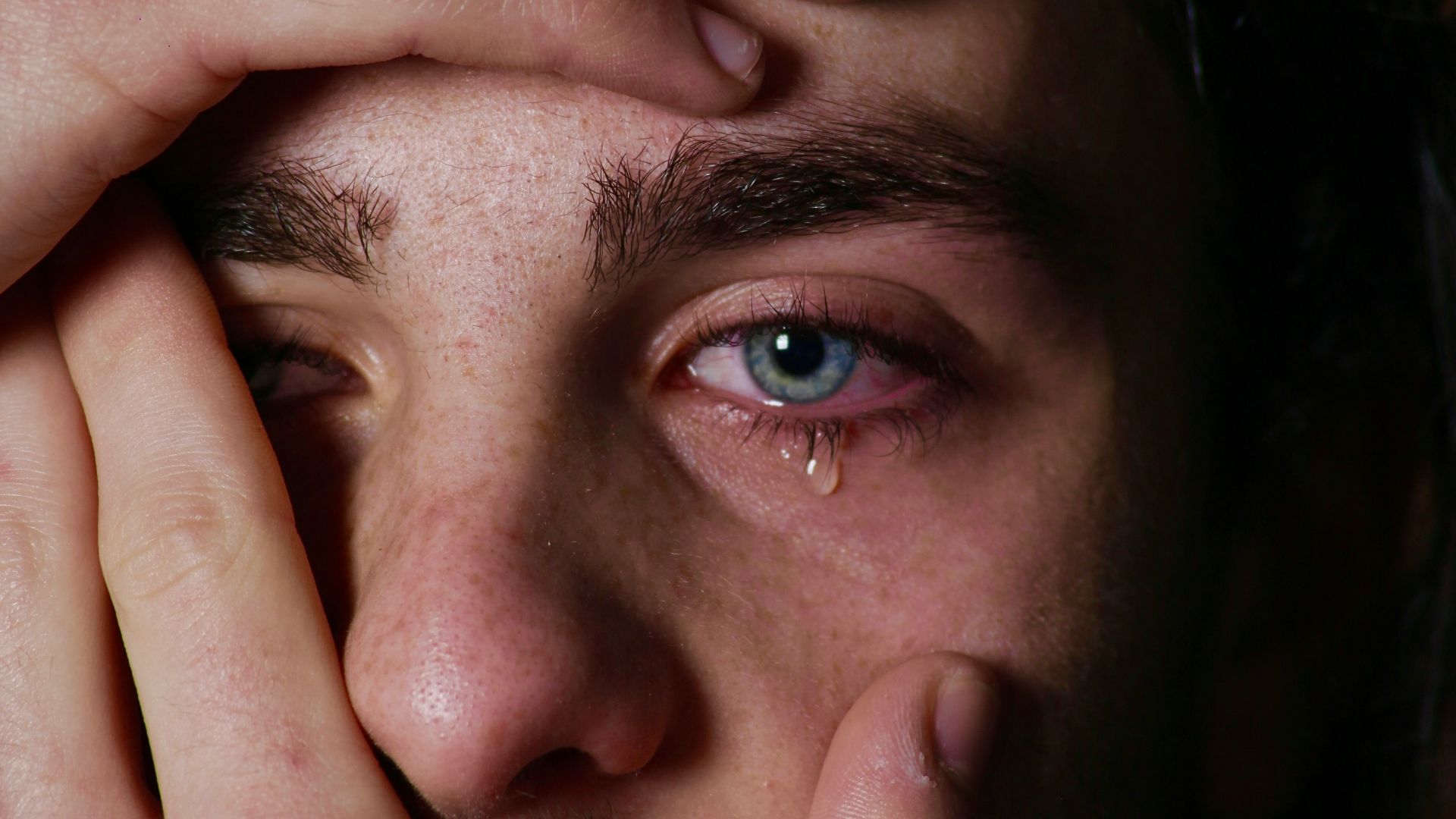 a man holding his hands to his face