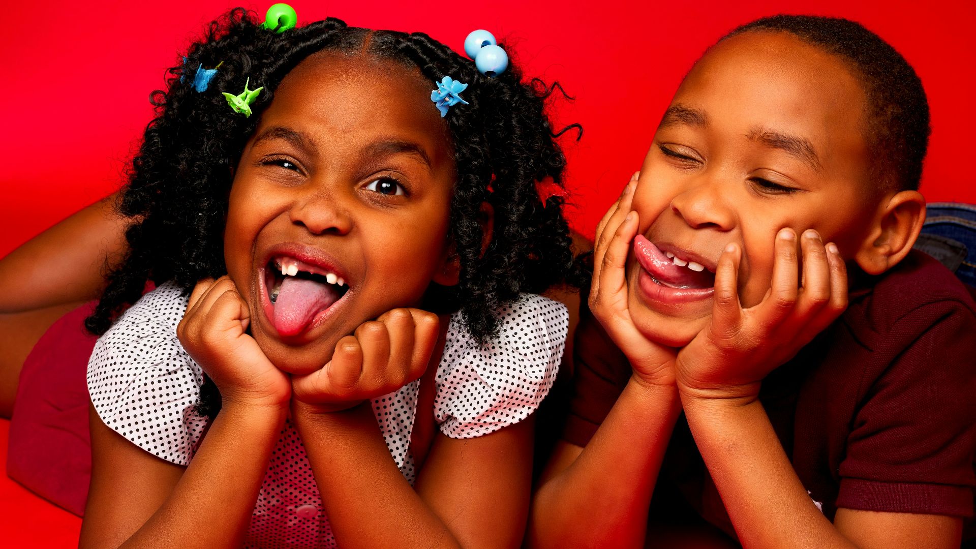 two little girls laying on the ground with their mouths open
