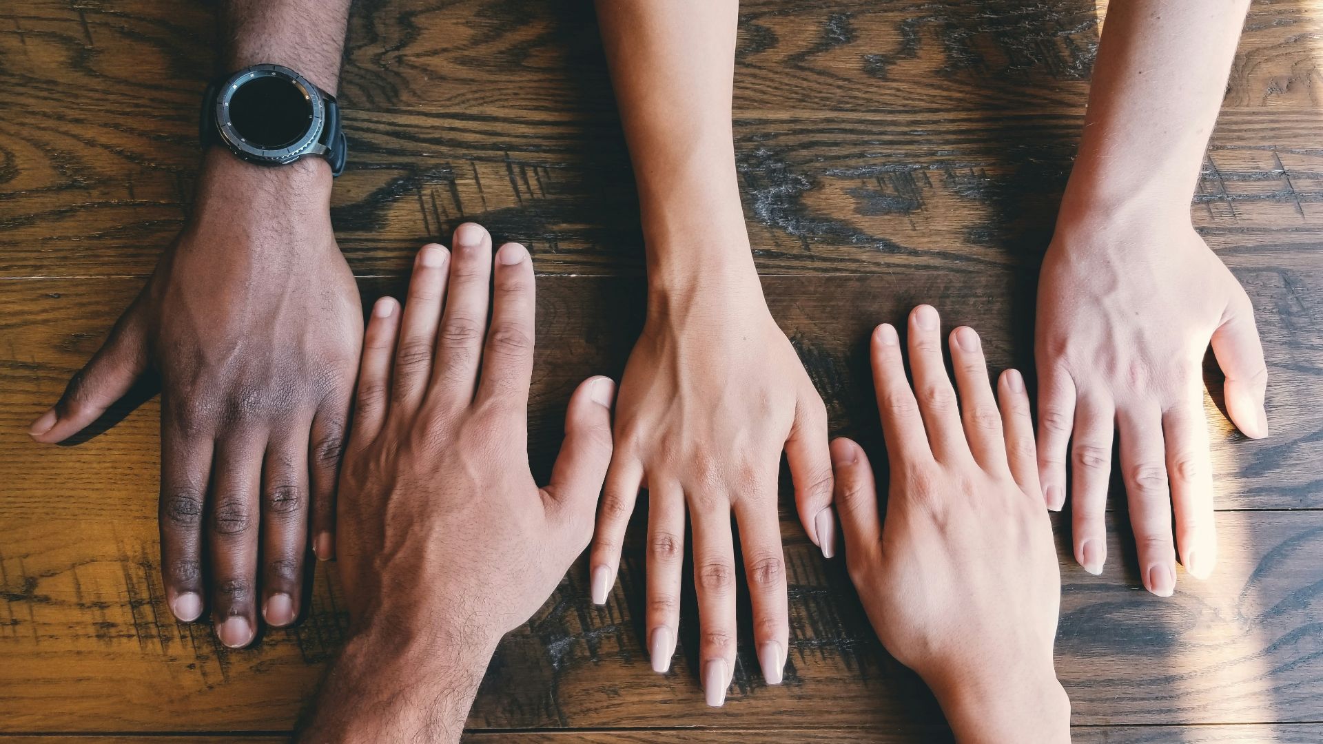 five human hands on brown surface
