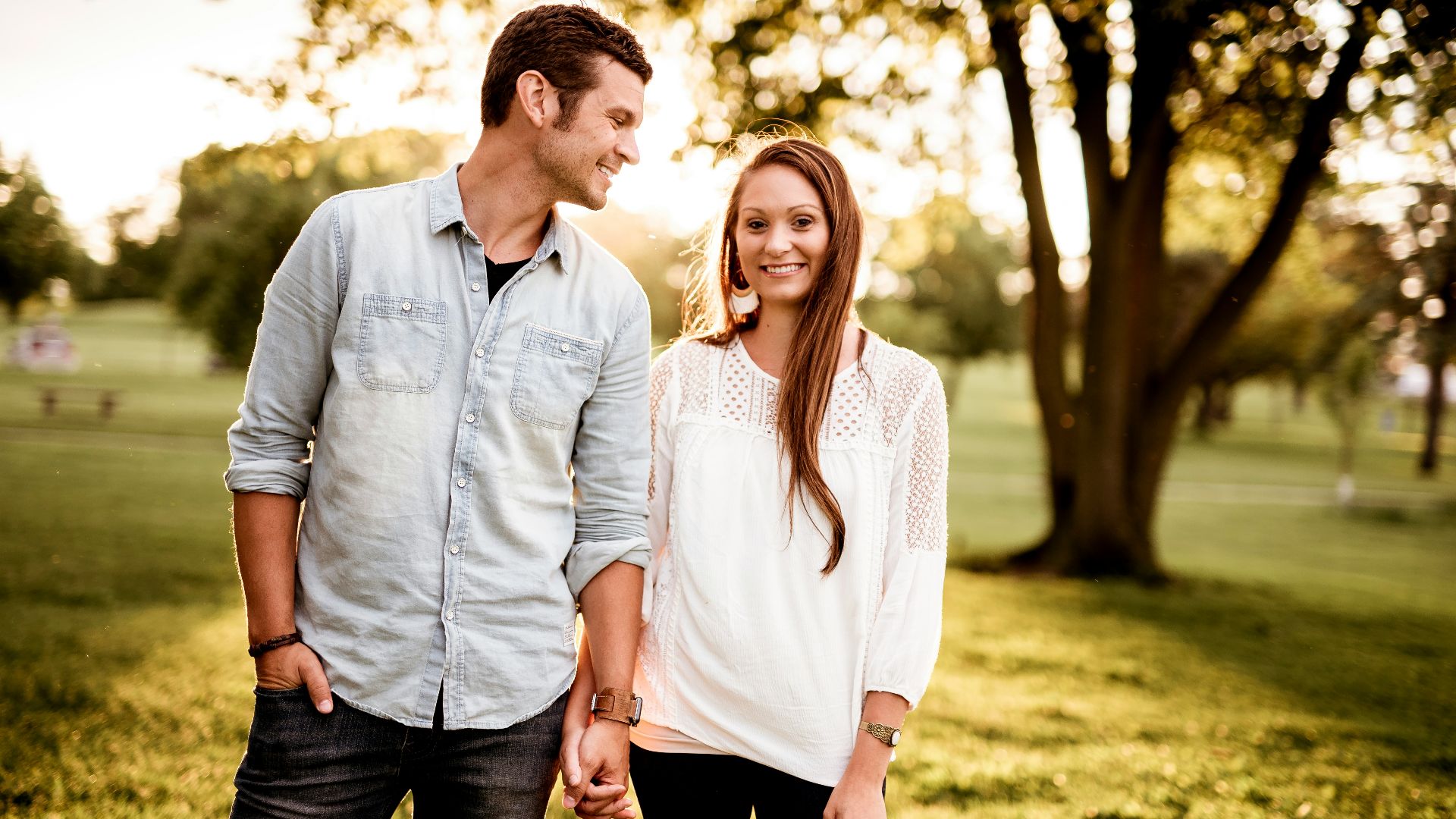 man holding hand of woman standing near tree