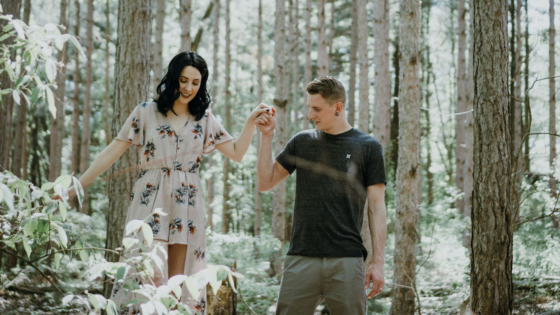 man holding hands with woman near trees
