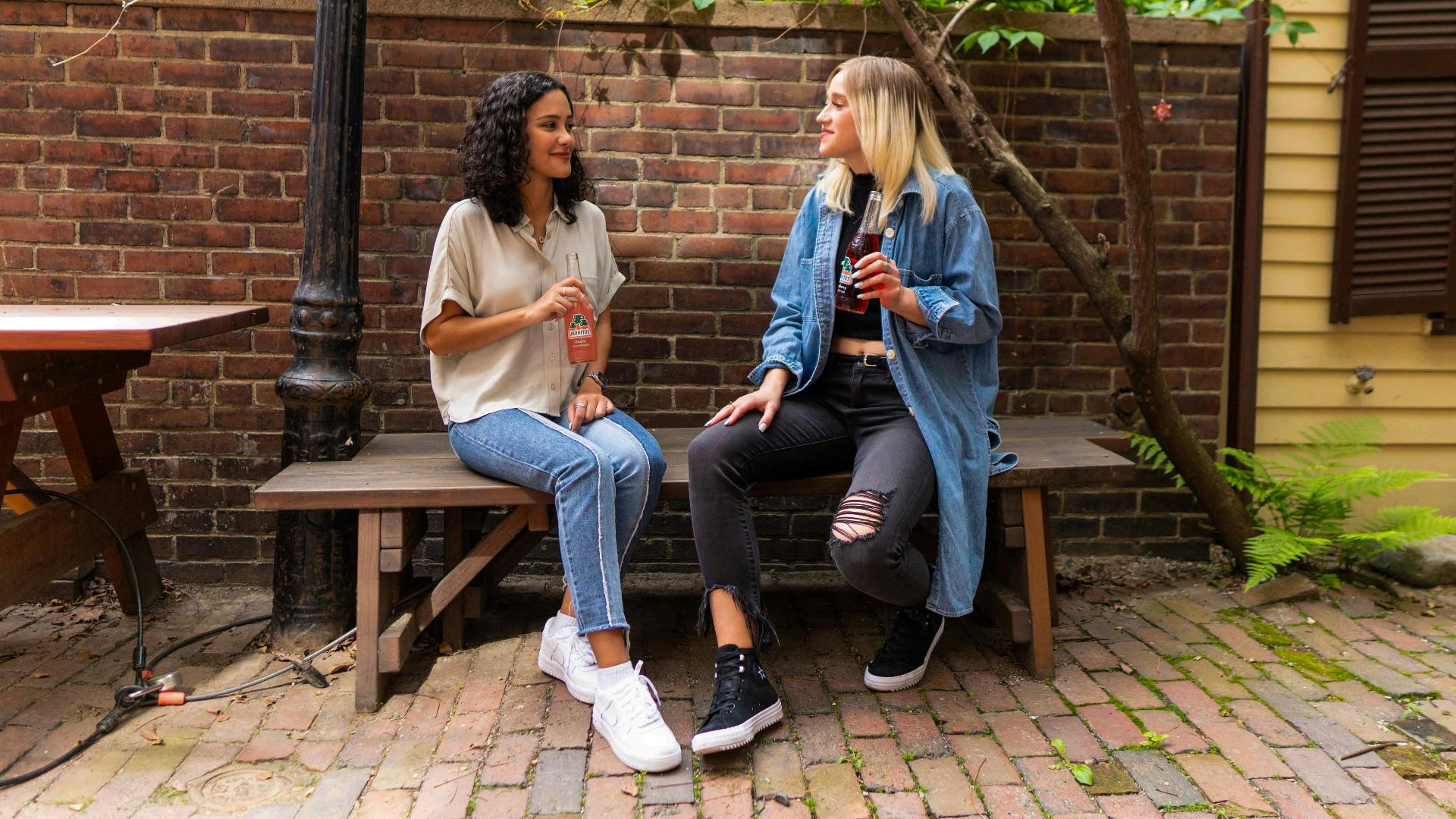 2 women sitting on brown wooden bench