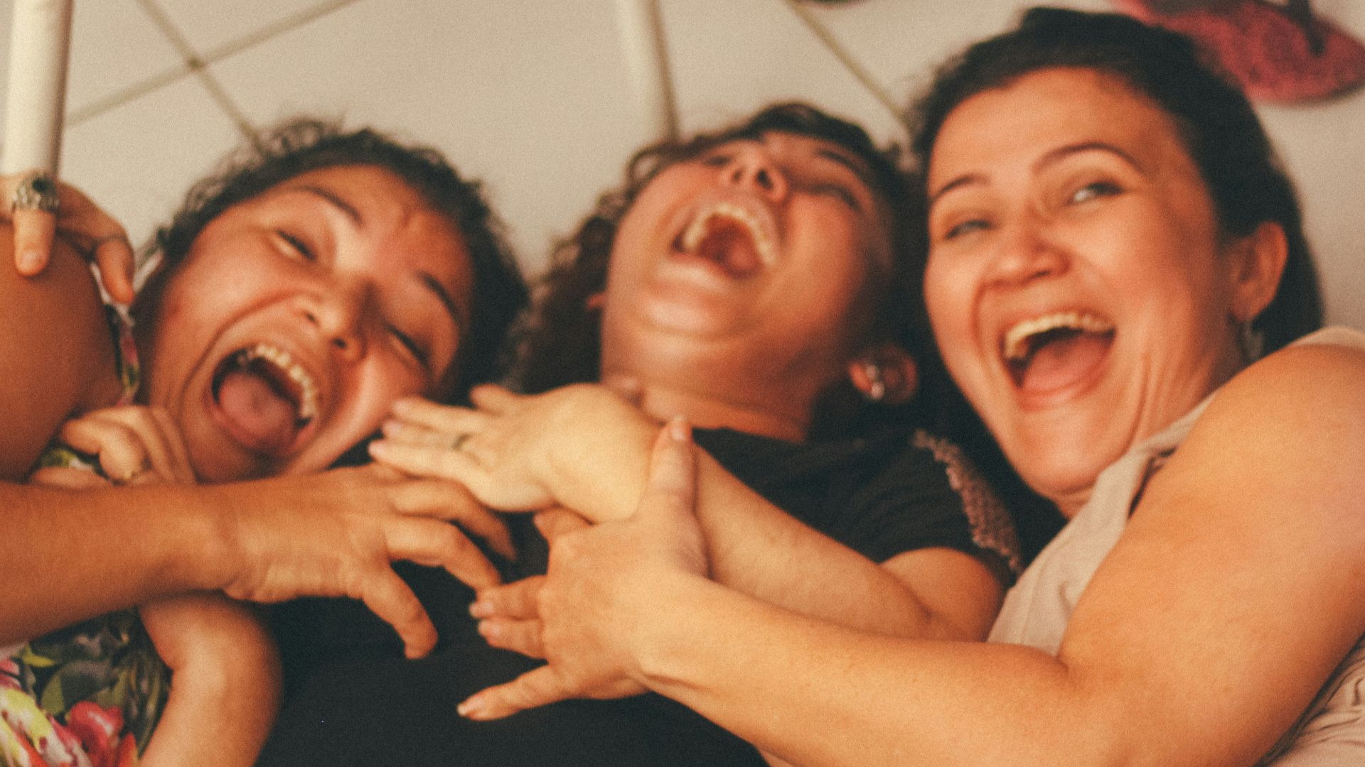3 women smiling and standing near white wall