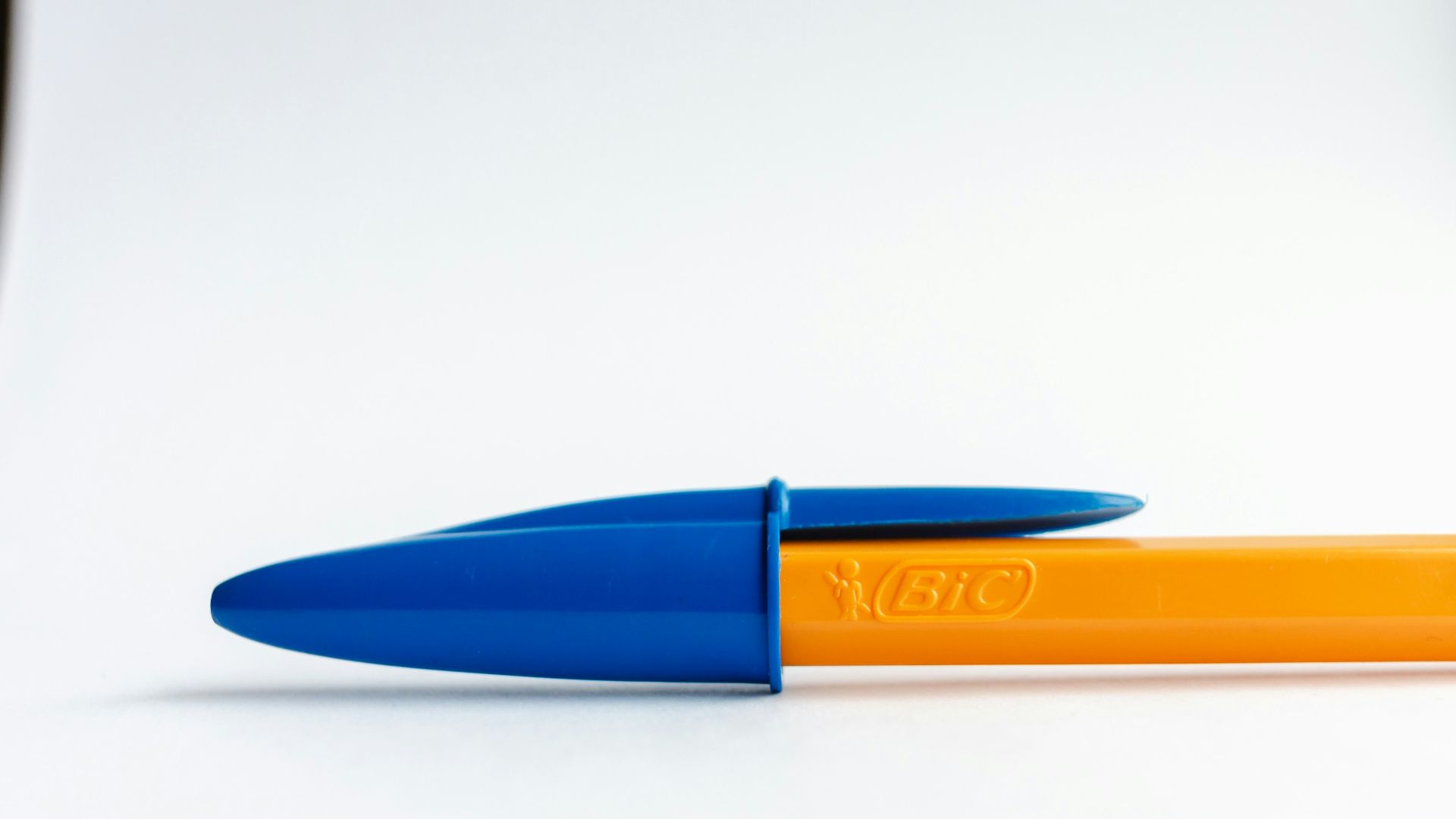 a blue and orange pen sitting on top of a white table