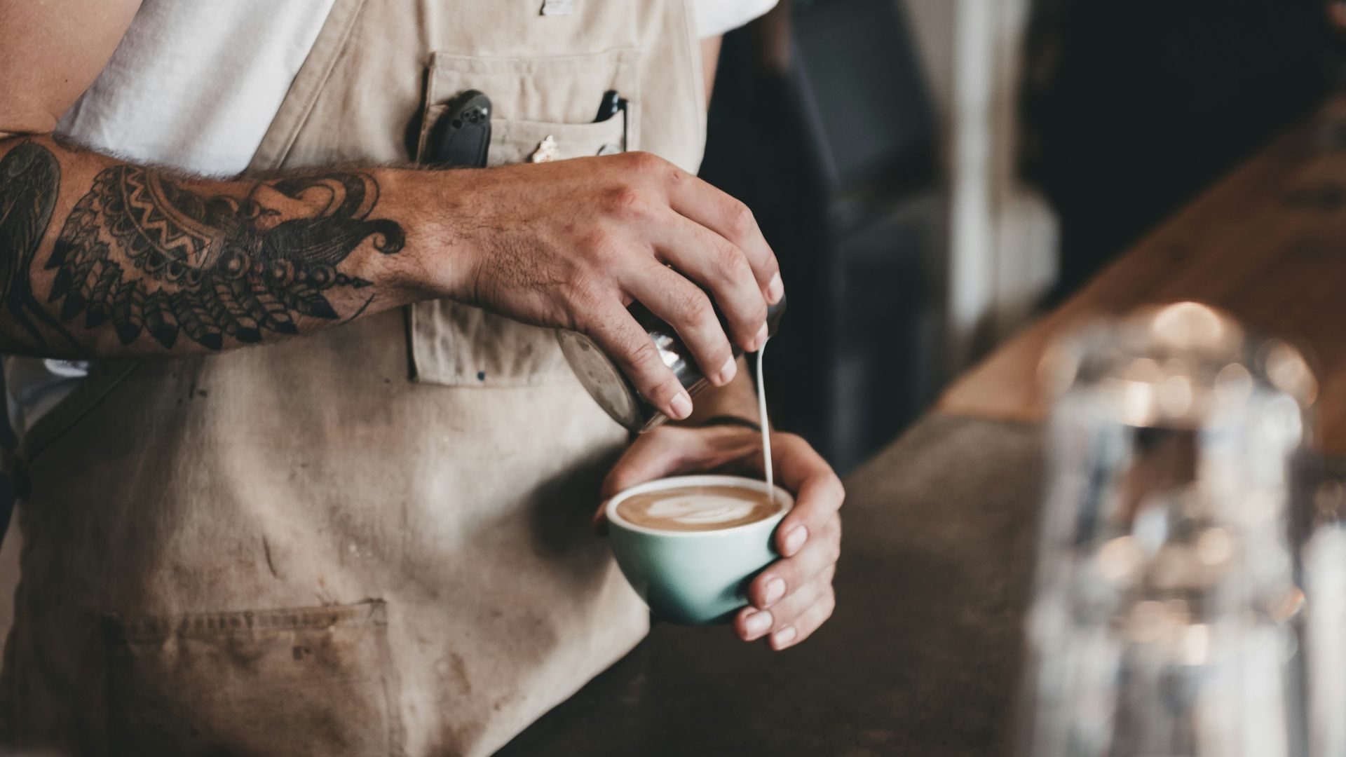 man pouring latte on coffee