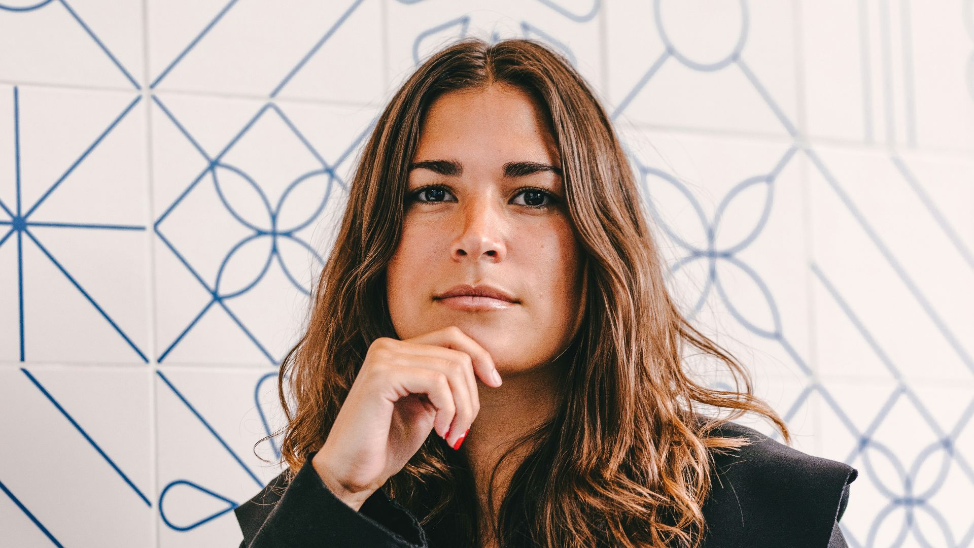 woman in black blazer covering her face with her hand