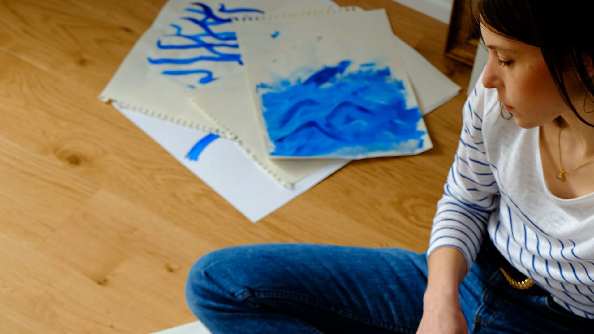 woman in white long sleeve shirt and blue denim jeans sitting on brown wooden table