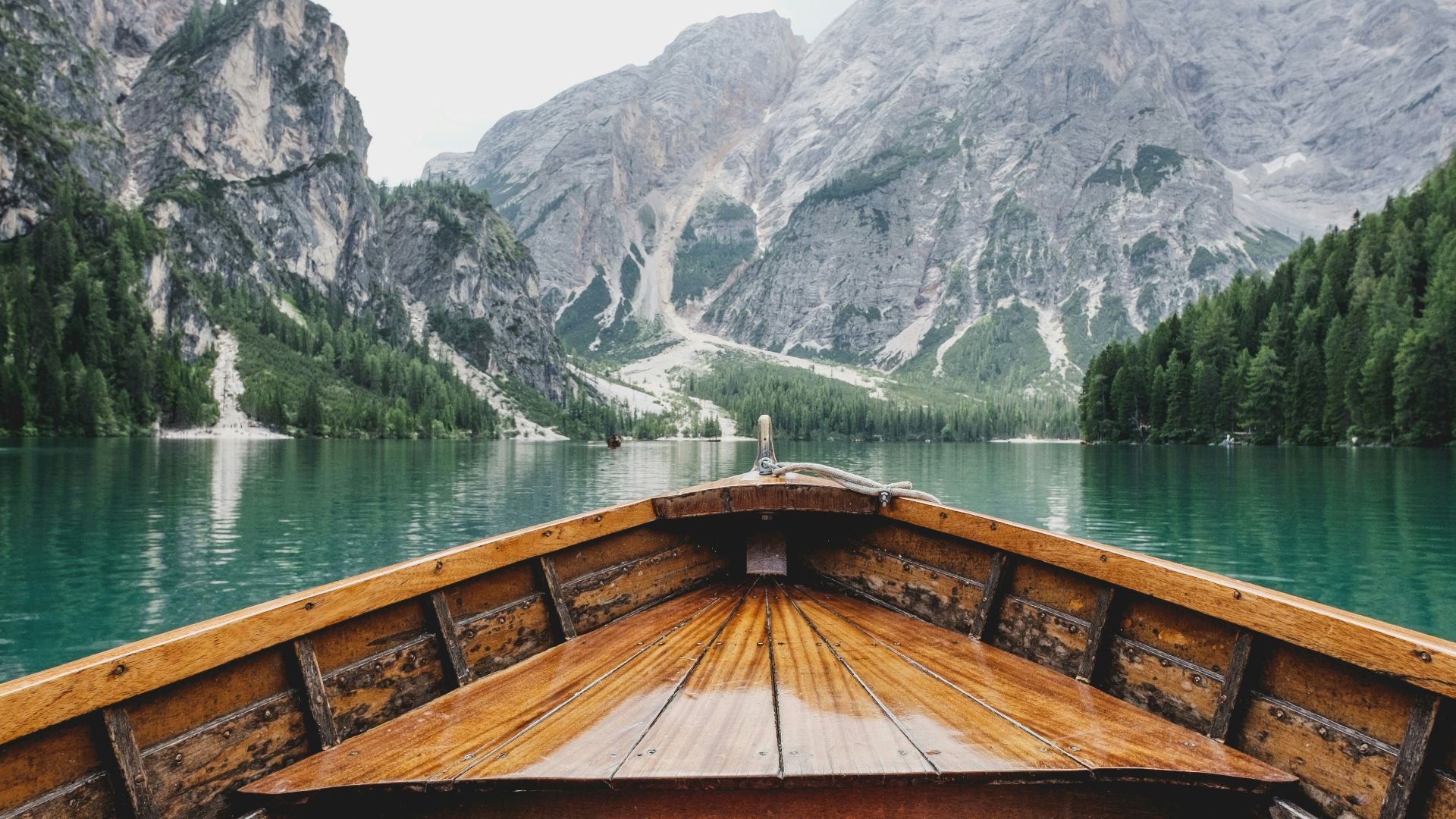brown wooden boat moving towards the mountain