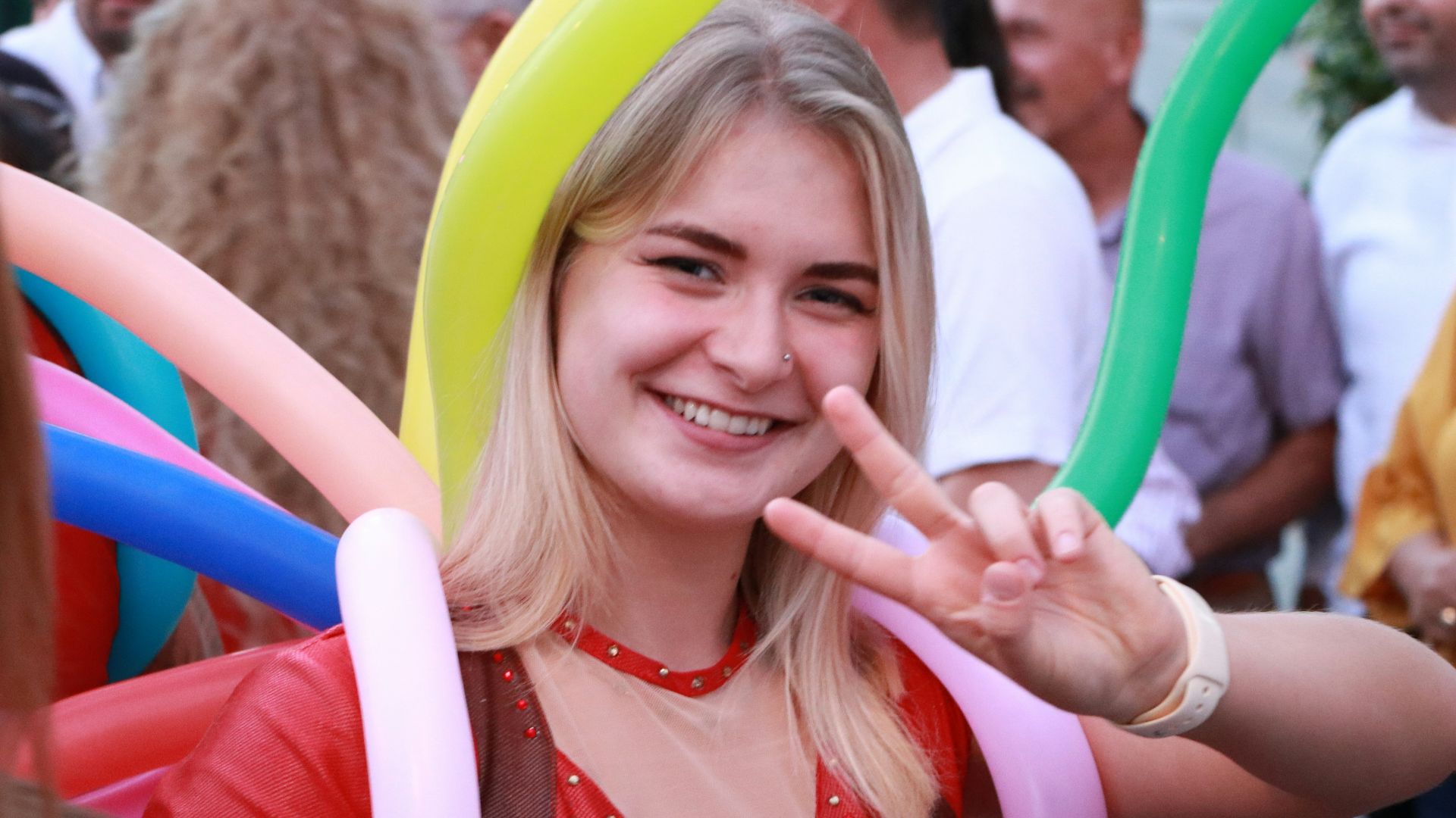 A woman smiles with balloons at an event.