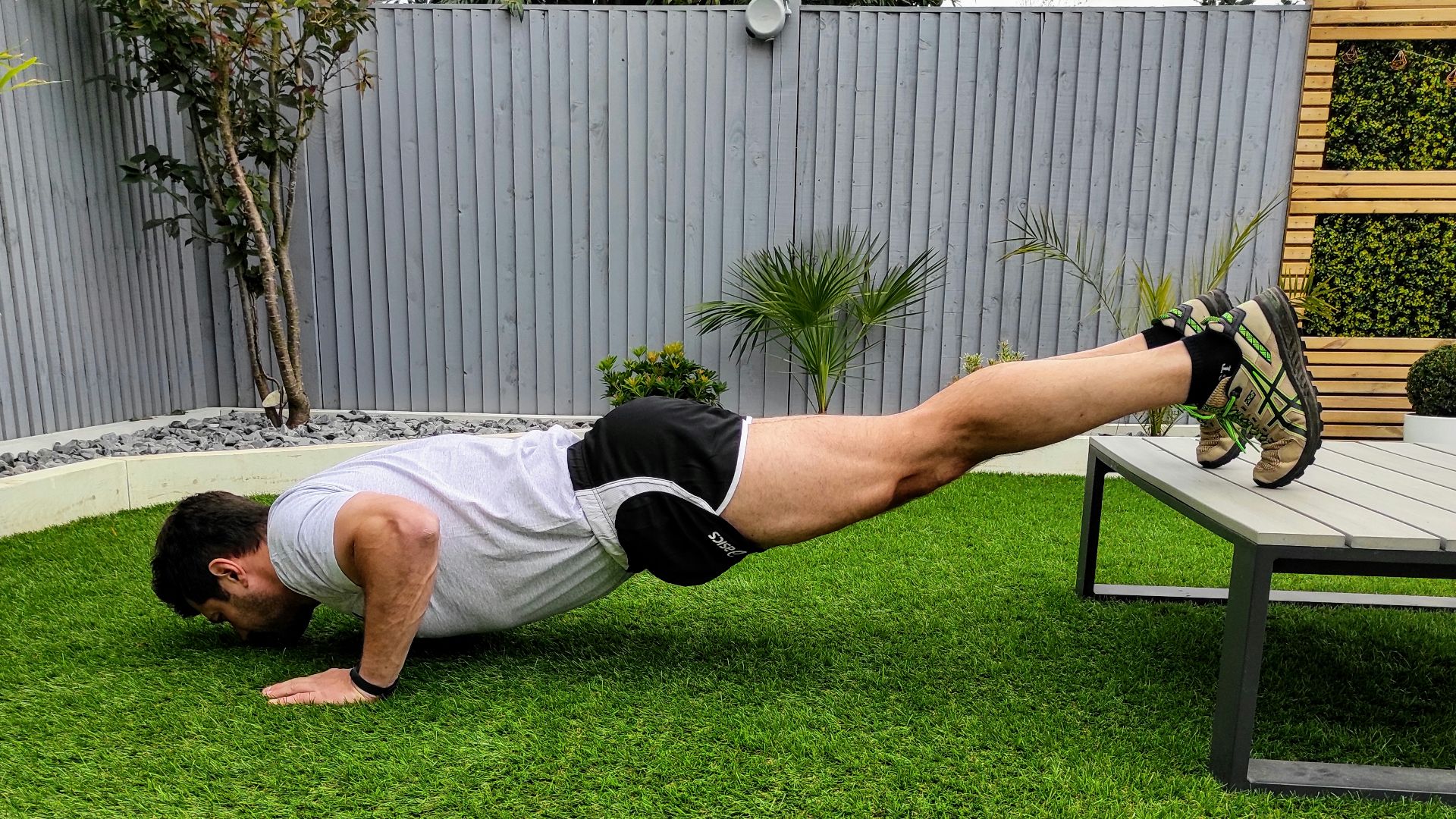 woman in white tank top and black shorts lying on green grass field during daytime