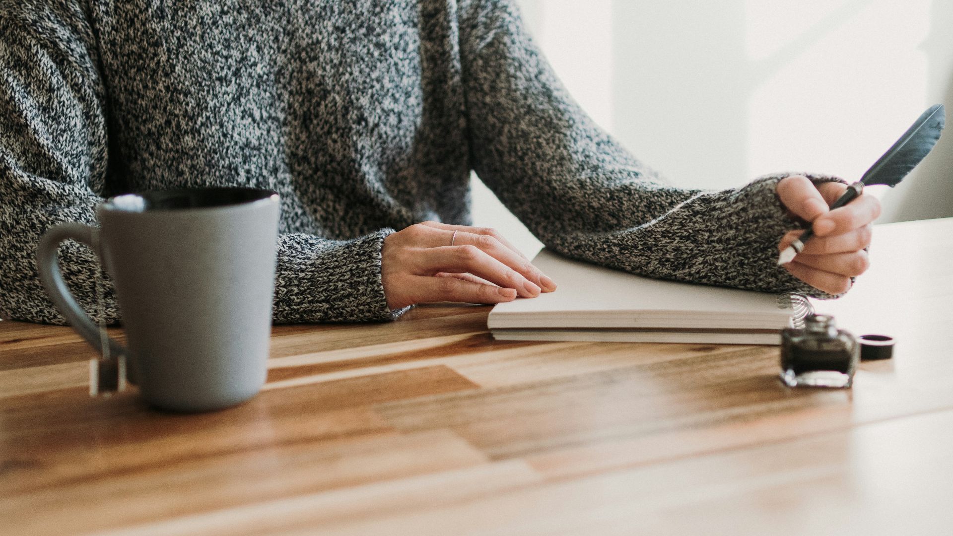 a woman sitting at a table writing on a notebook