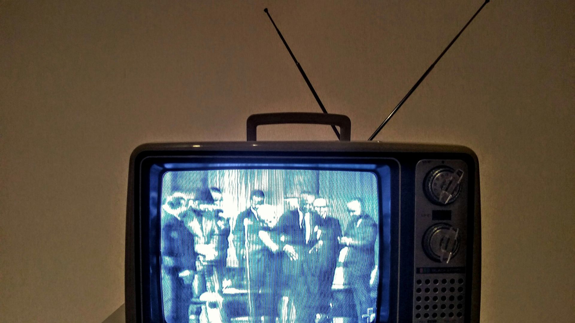 black crt tv turned on on white table