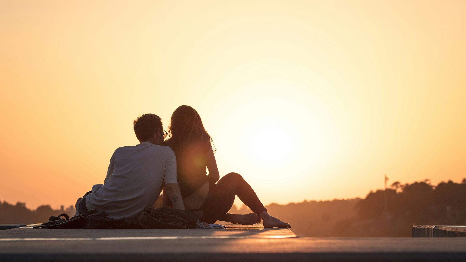 couple sitting near trees during golden hour
