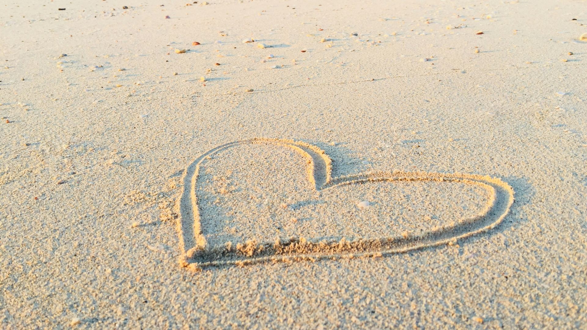 heart drawn on sand during daytime