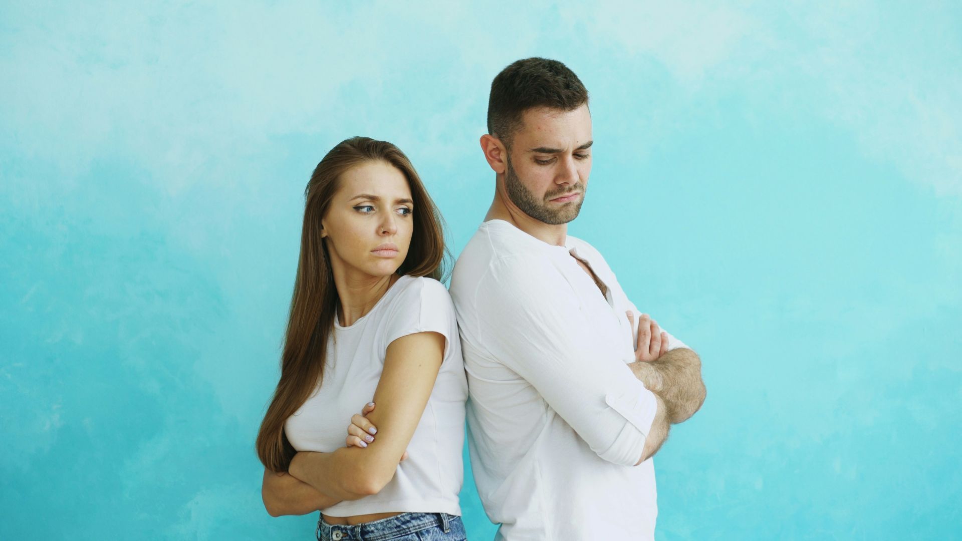 Couple standing back to back with arms crossed