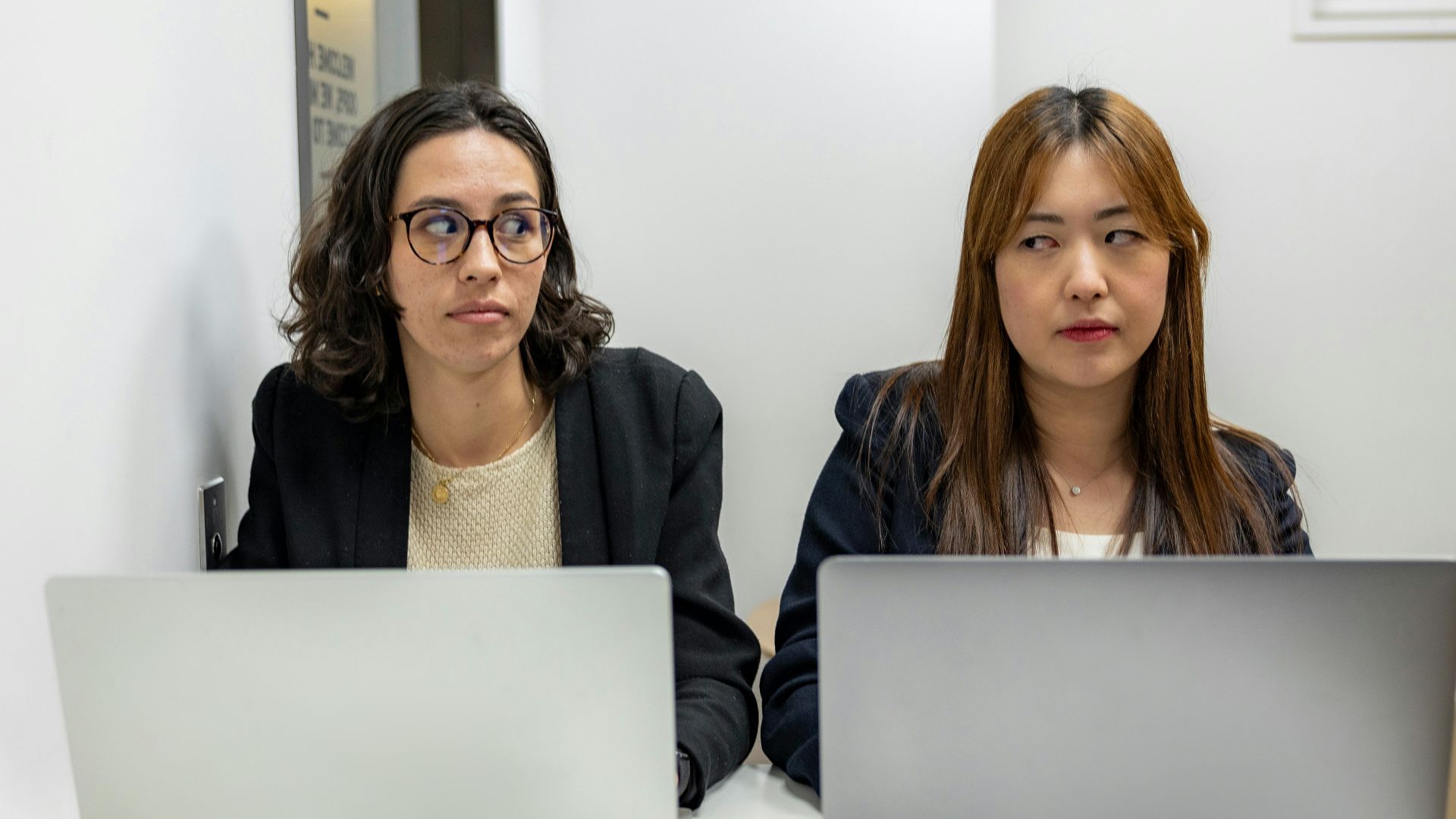 two women sitting at a table with laptops