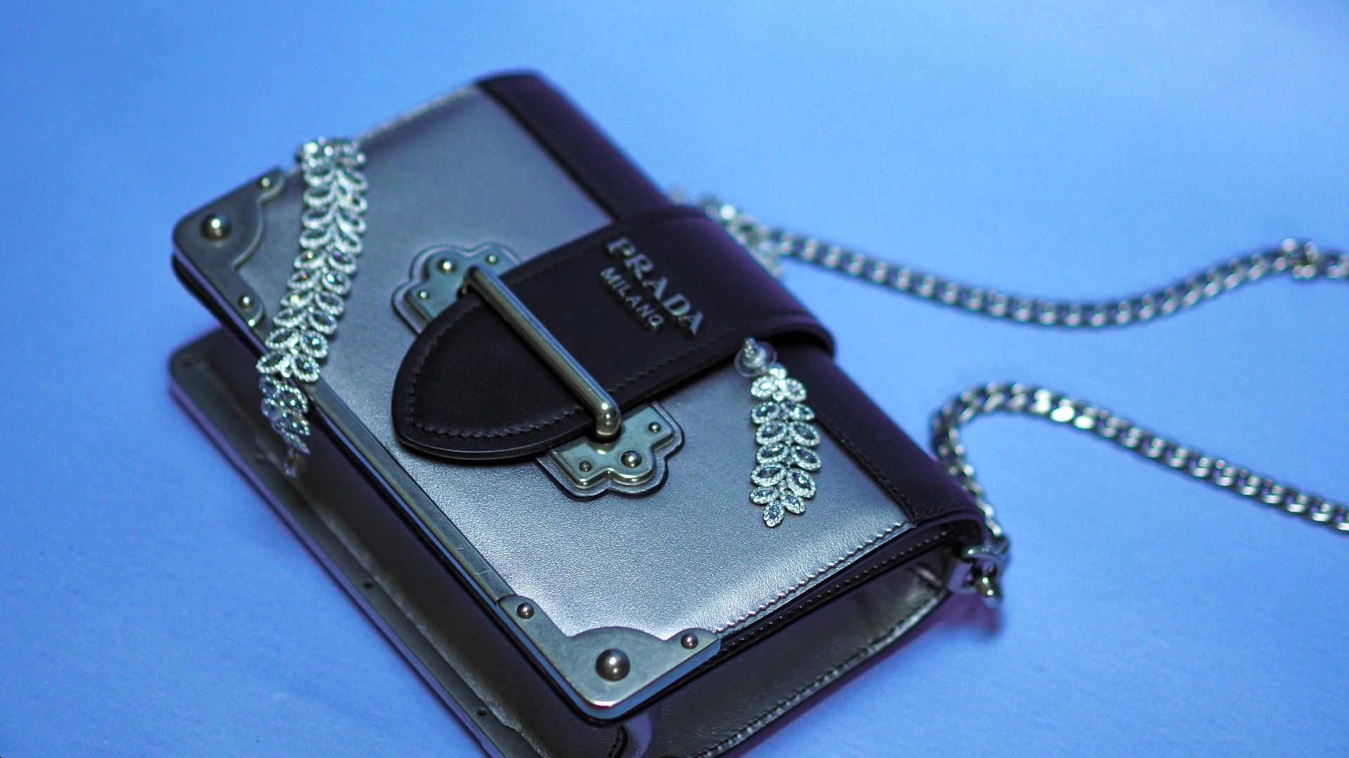 black leather sling bag on blue textile