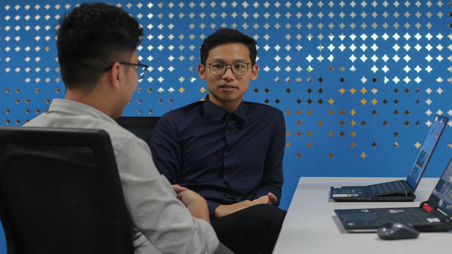 two men sitting at a table talking to each other