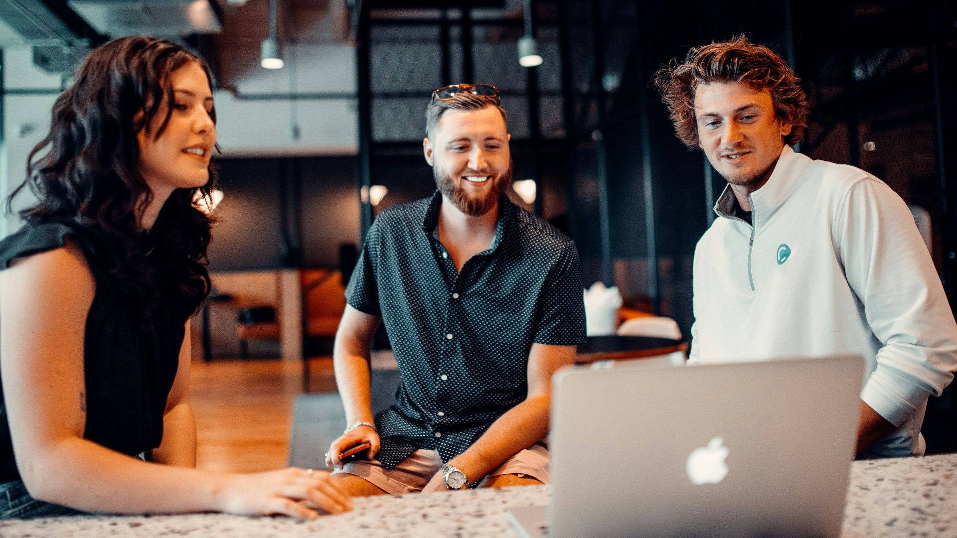 a group of people sitting around a laptop computer