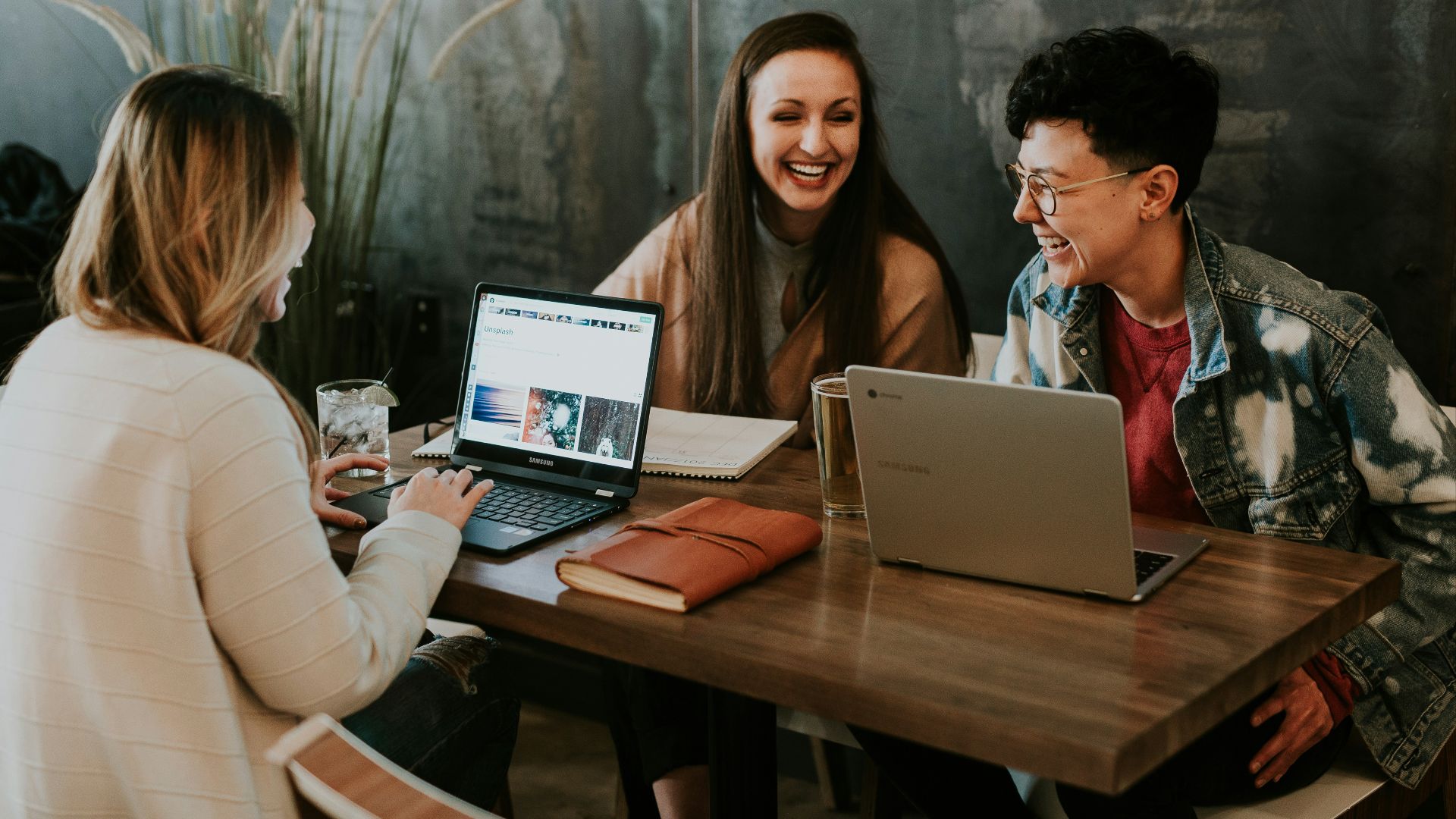 three people sitting in front of table laughing together