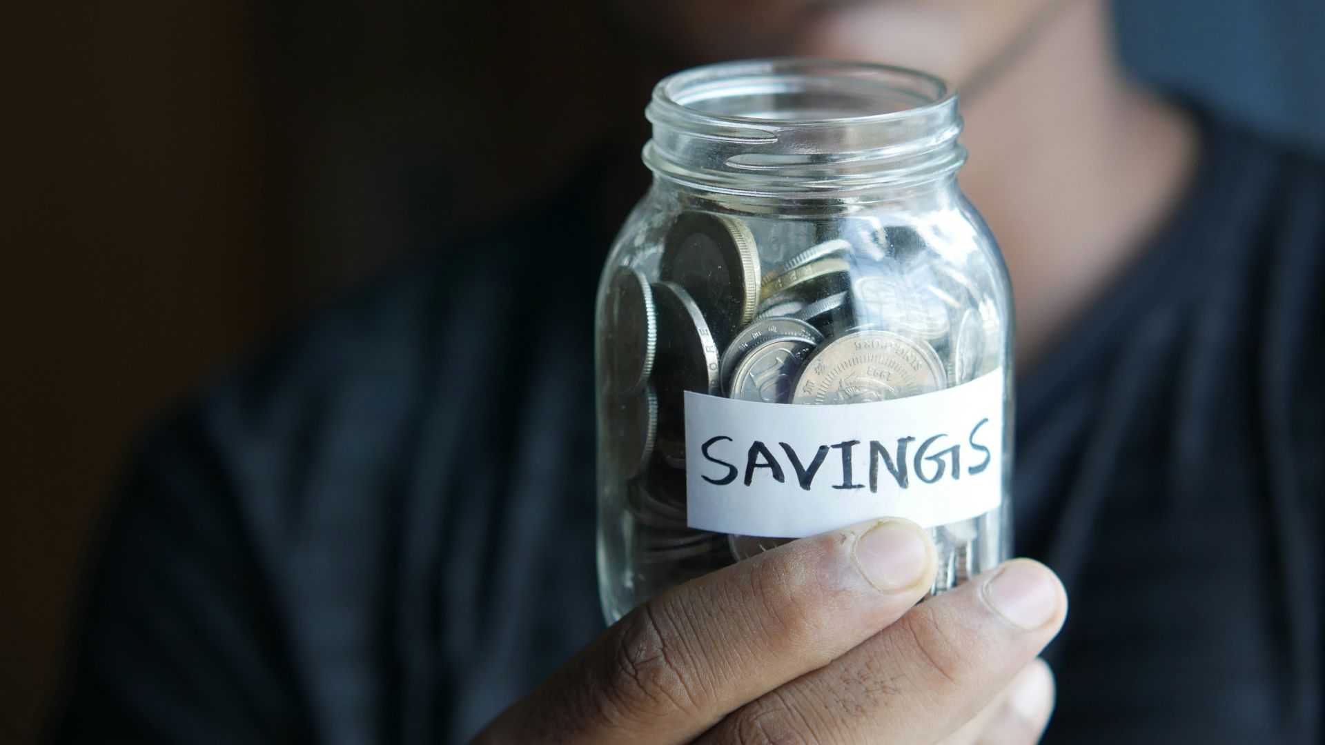 a man holding a jar with a savings label on it