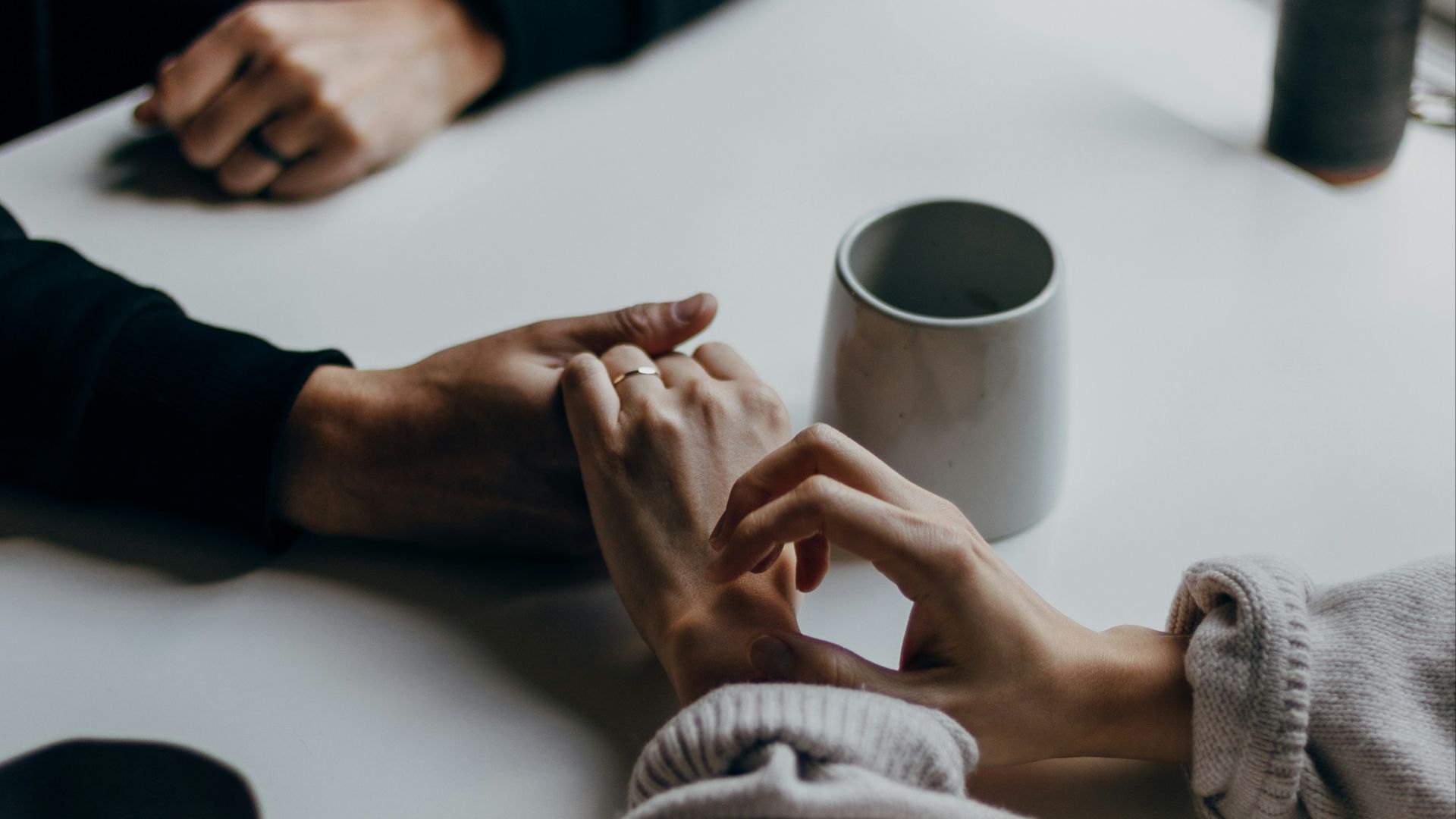 person in black long sleeve shirt holding white ceramic mug