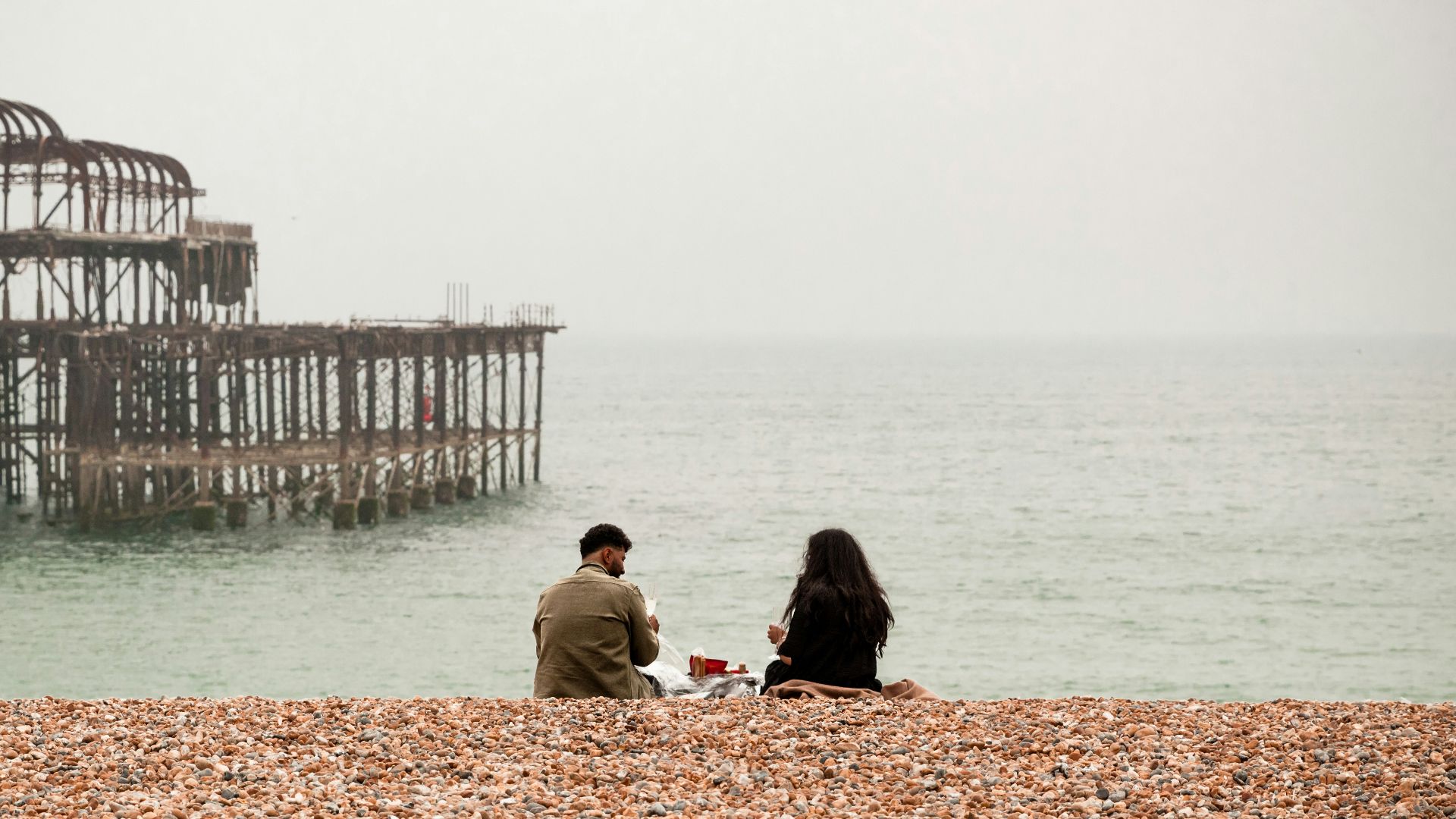 people sitting on brown sand near body of water during daytime