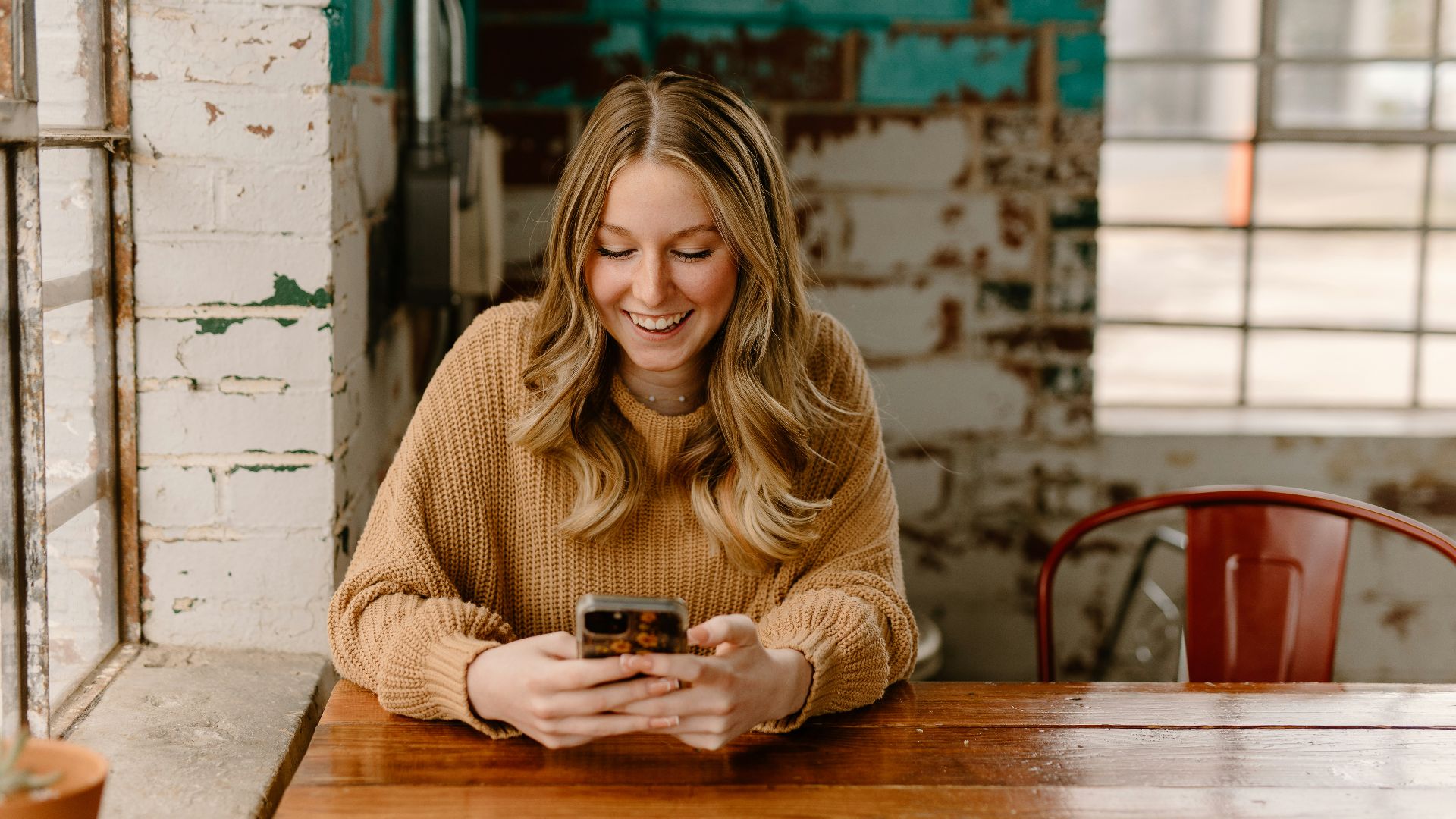 a woman sitting at a table looking at her cell phone