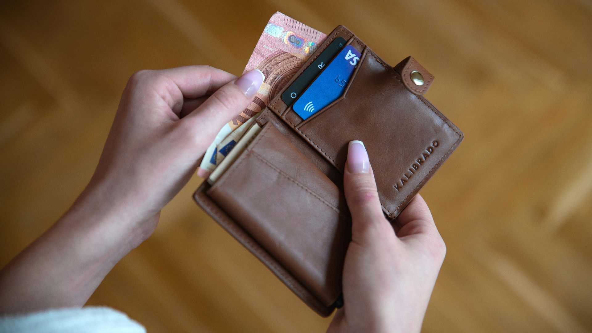 person holding brown leather card wallet