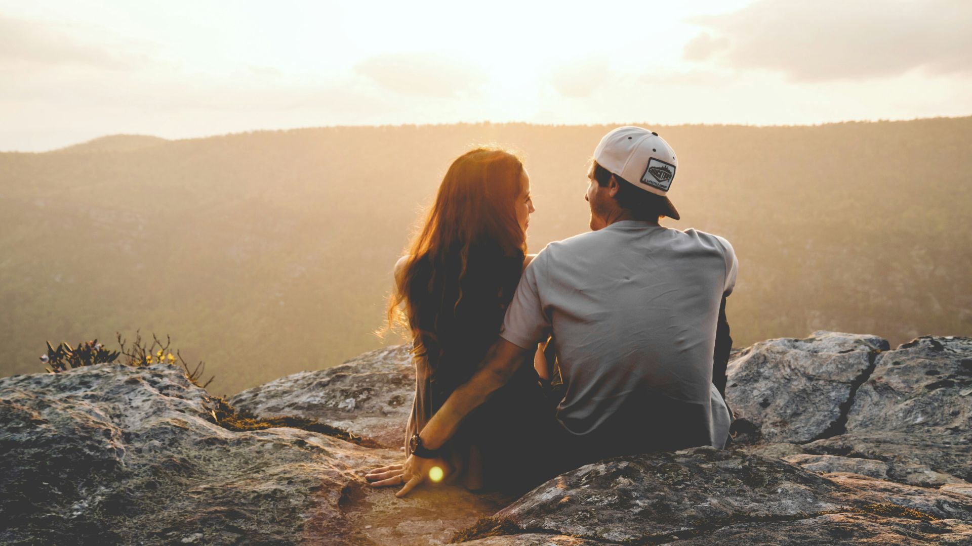 man and woman sitting on rock during daytime