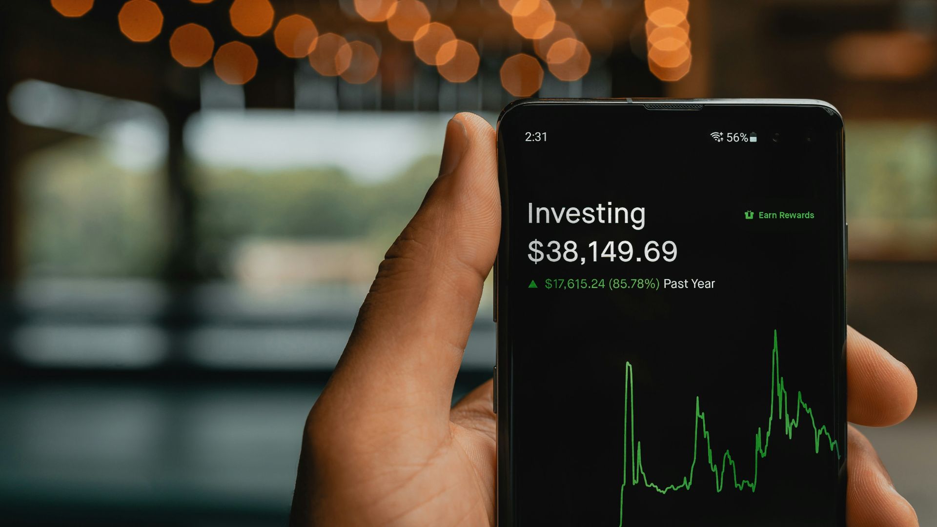 a person holding up a cell phone with a stock chart on it