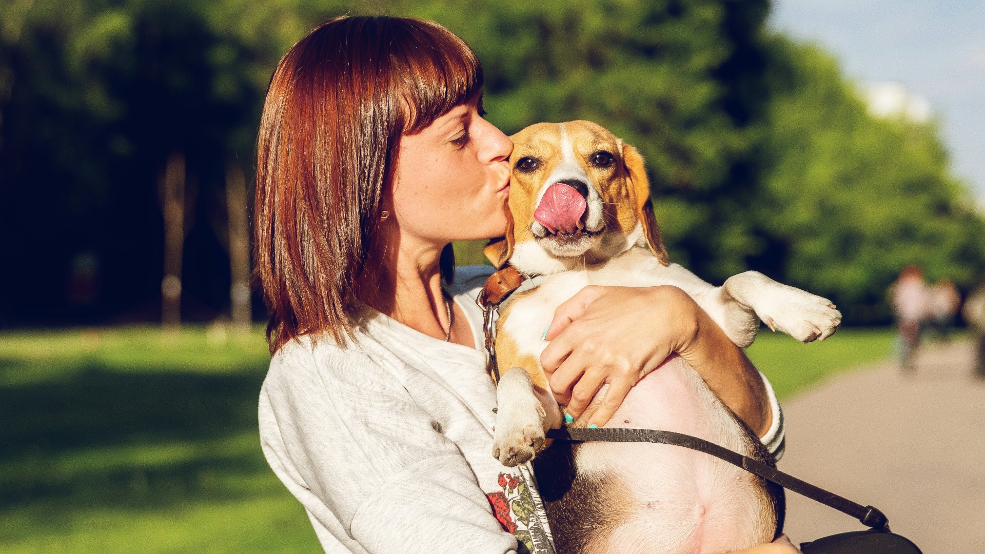 woman carrying and kissing dog
