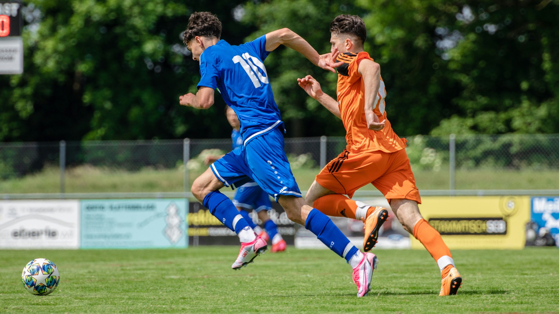 man in blue and orange jersey shirt running on green grass field during daytime