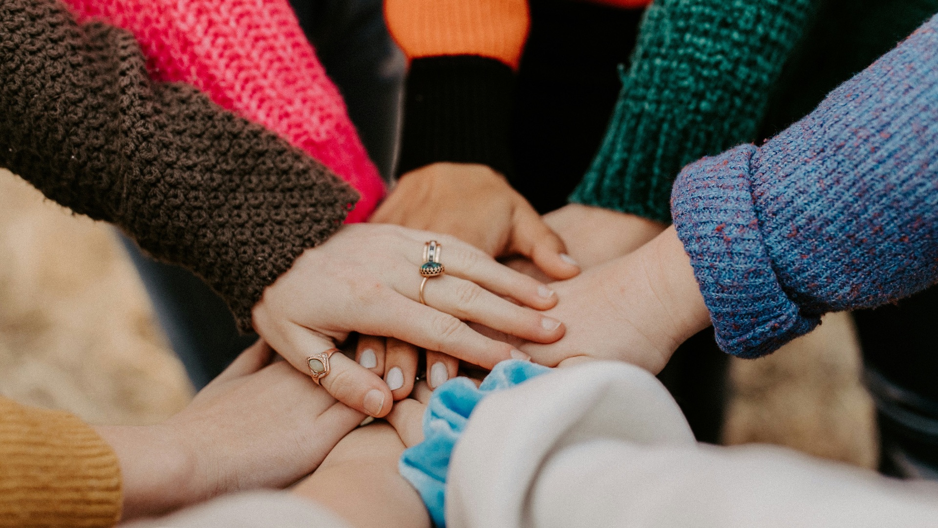 person in red sweater holding babys hand