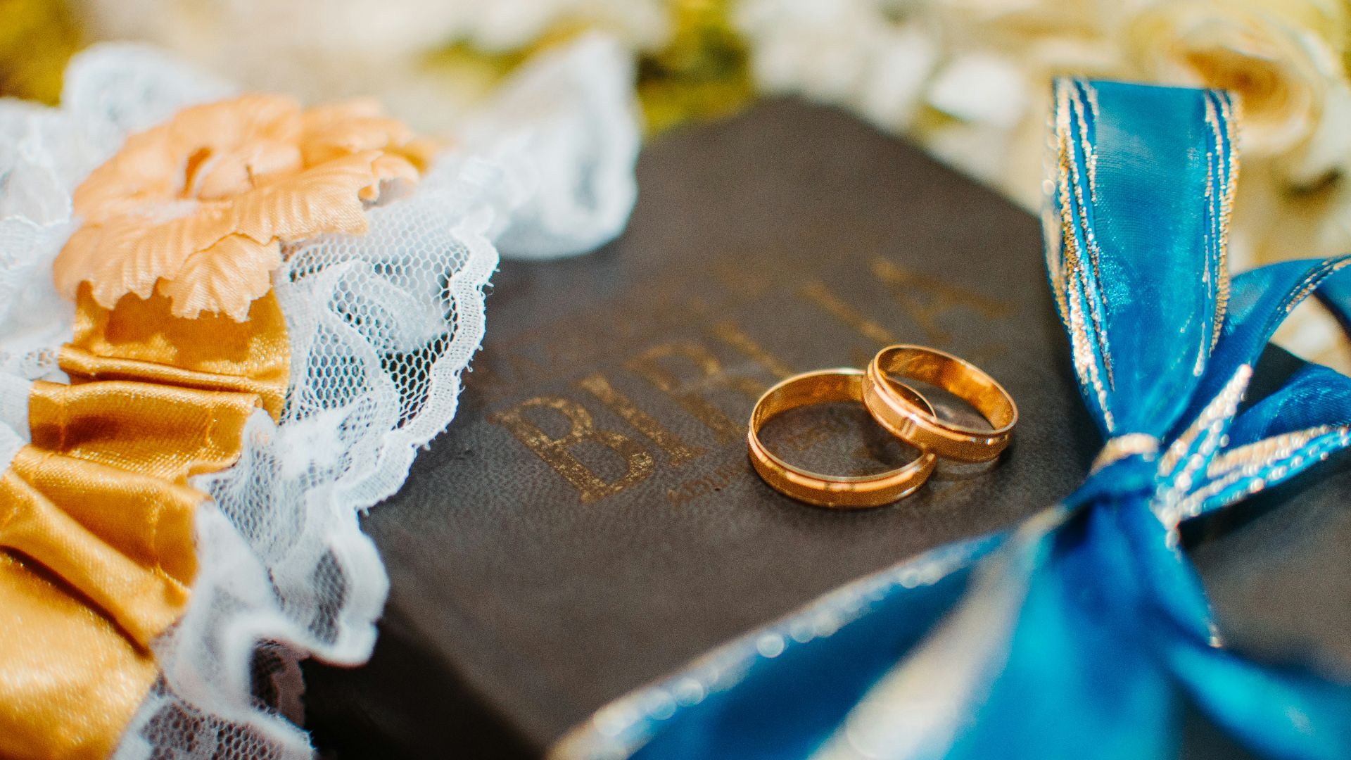 gold-colored wedding rings on Bible scripture