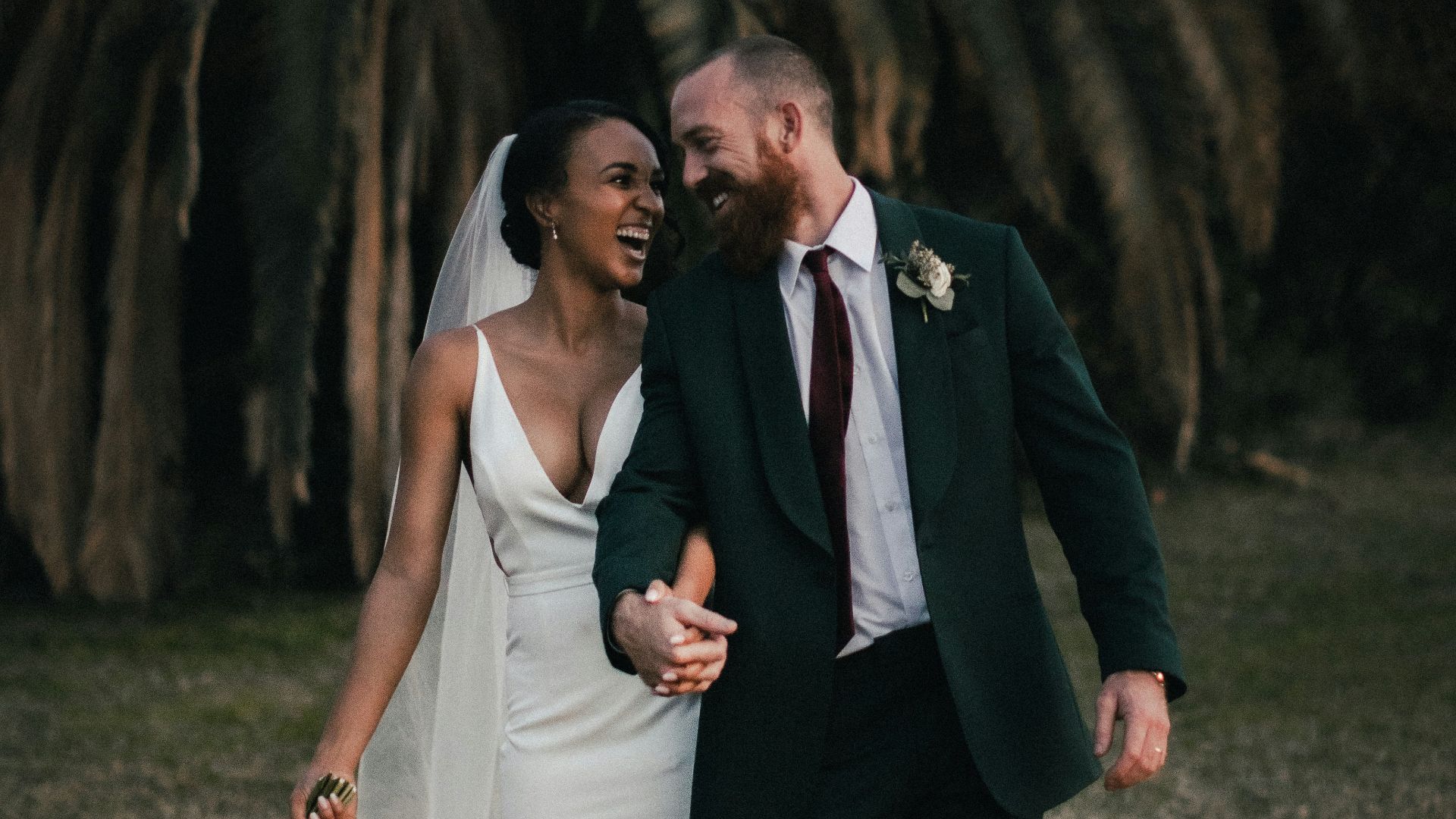 a newly married couple walking through a field