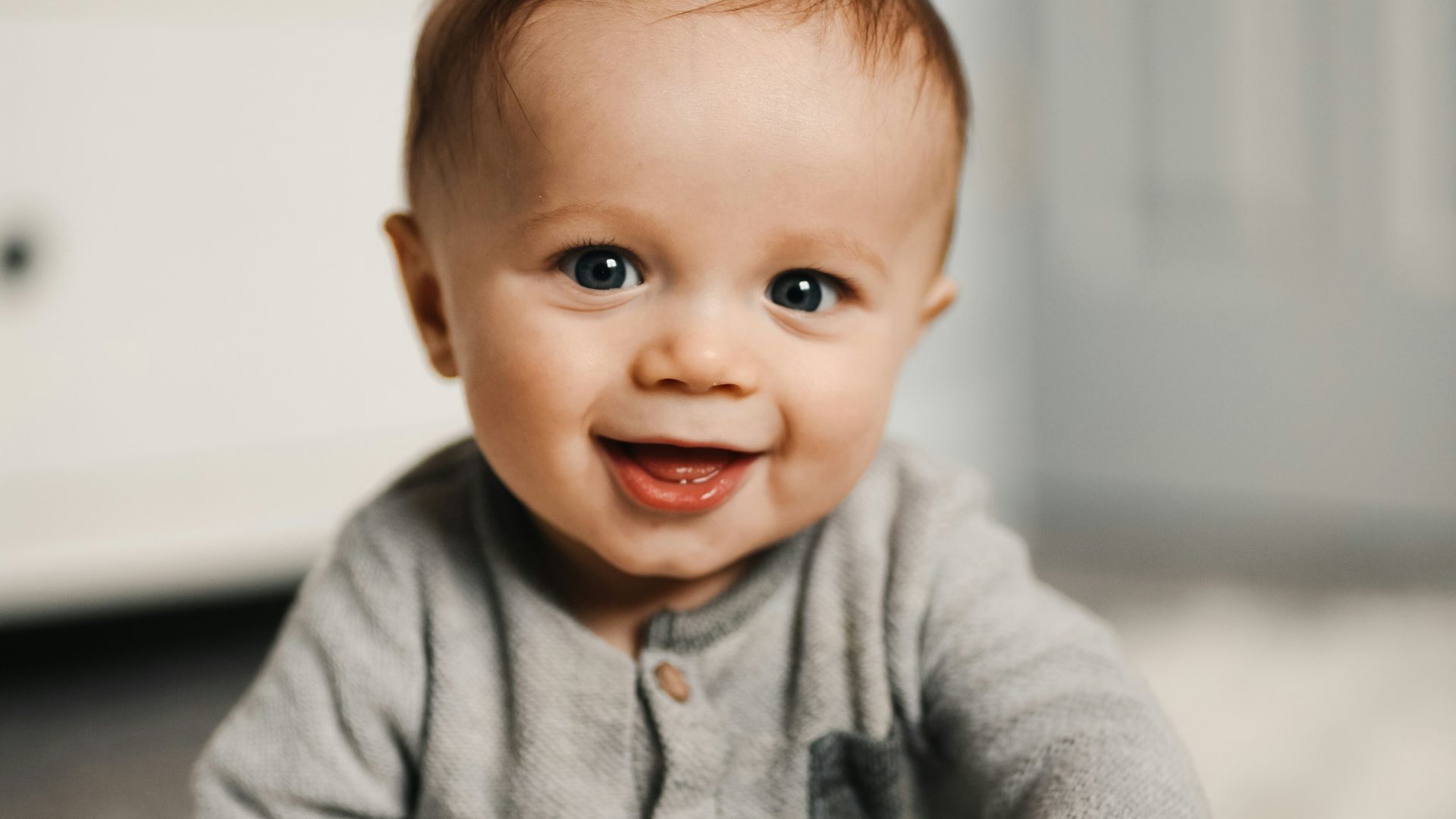 baby in gray sweater lying on white textile