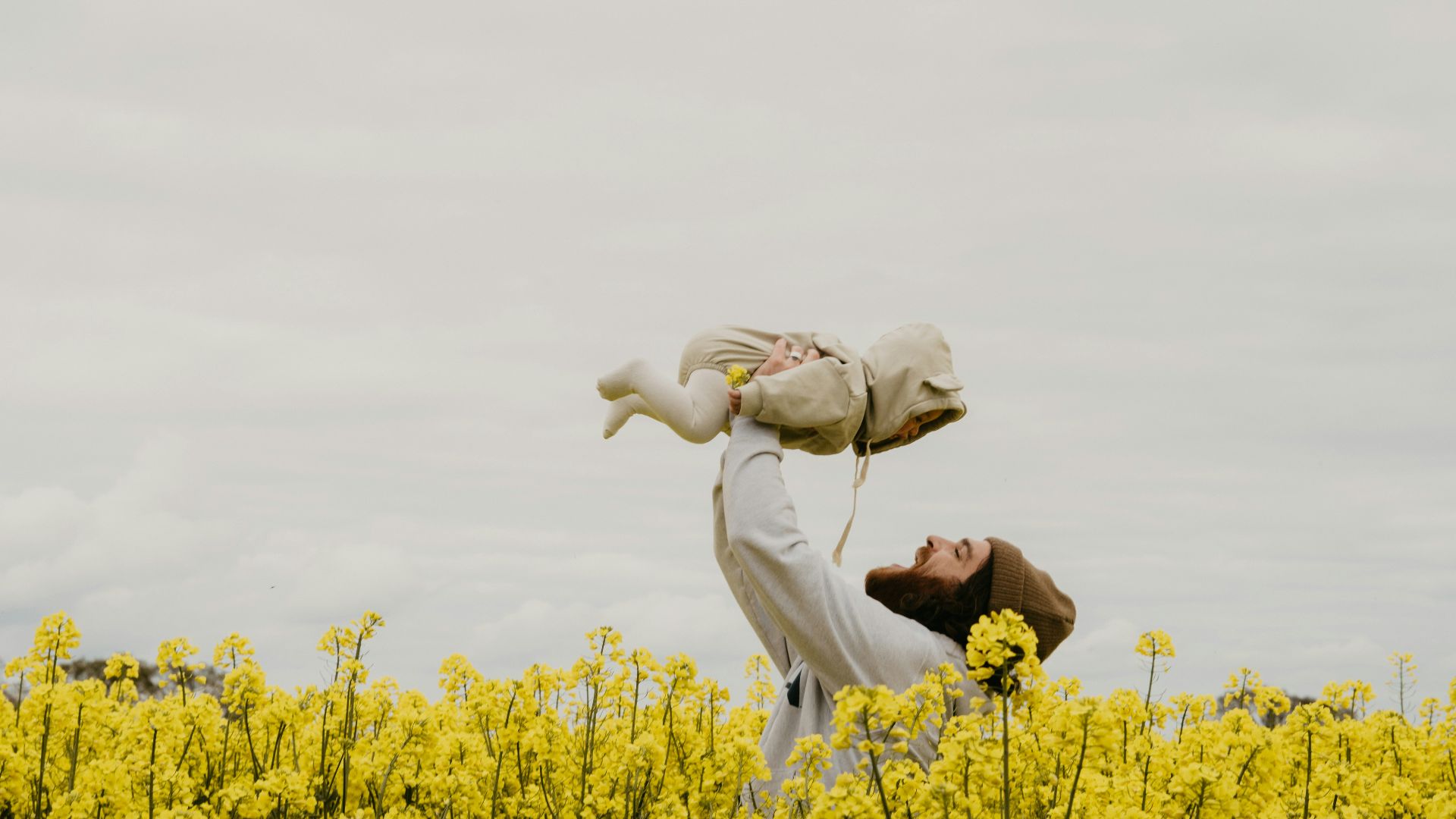 a person holding a baby in a field of yellow flowers