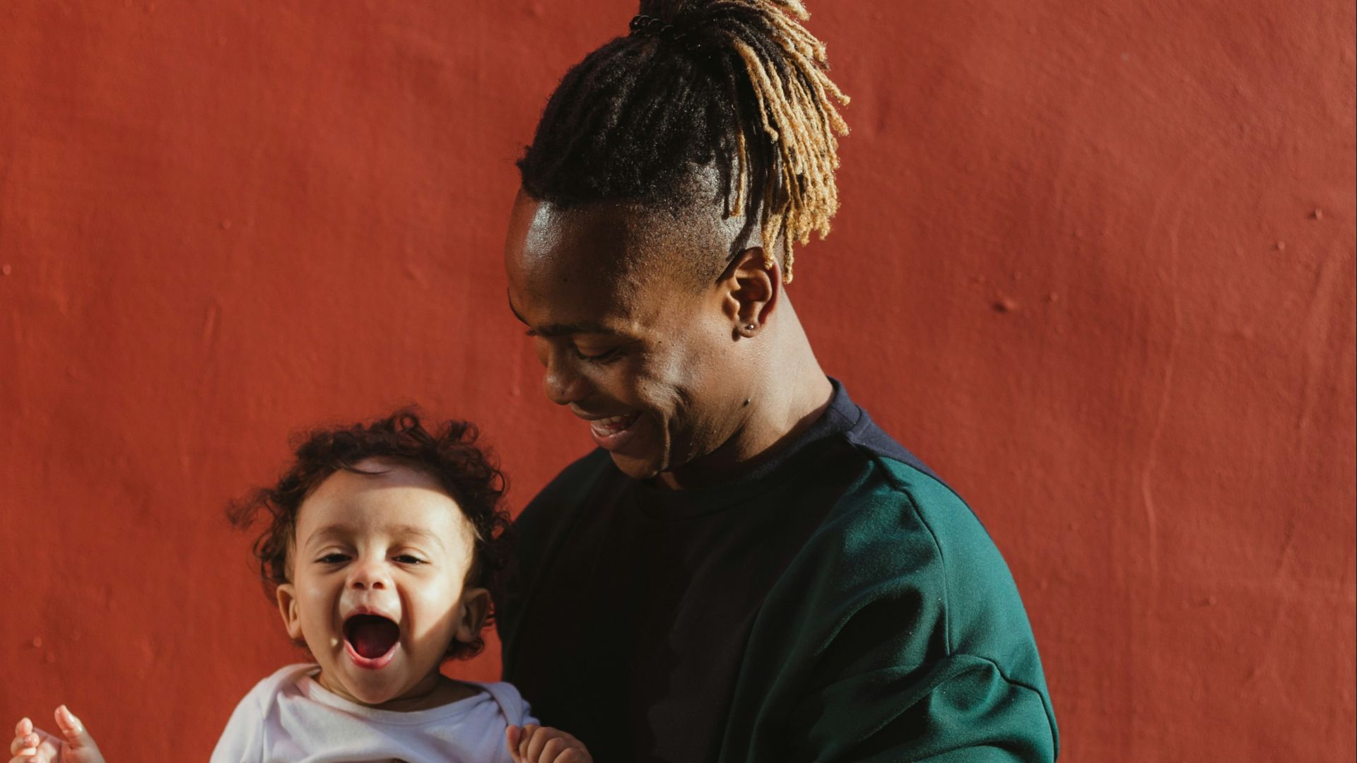 smiling man carrying child and playing