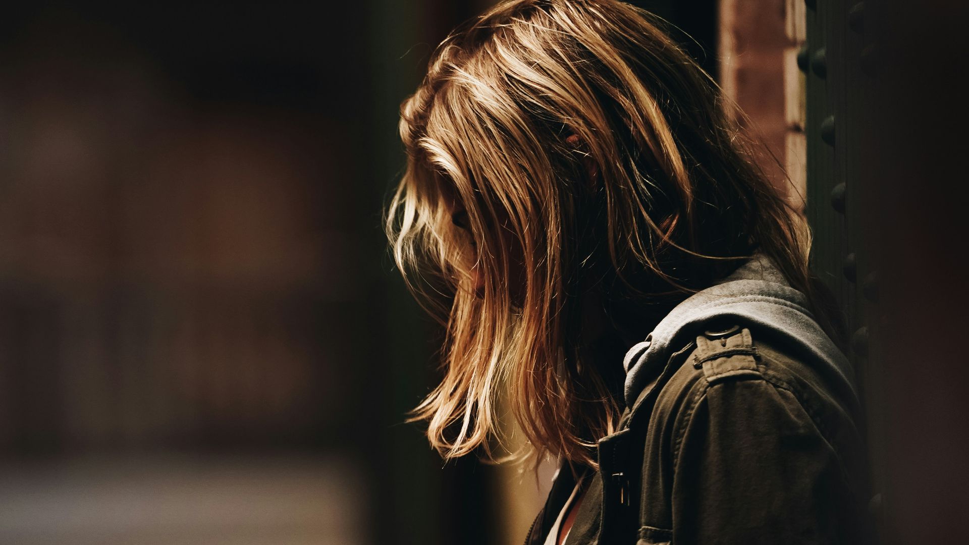 woman leaning against a wall in dim hallway