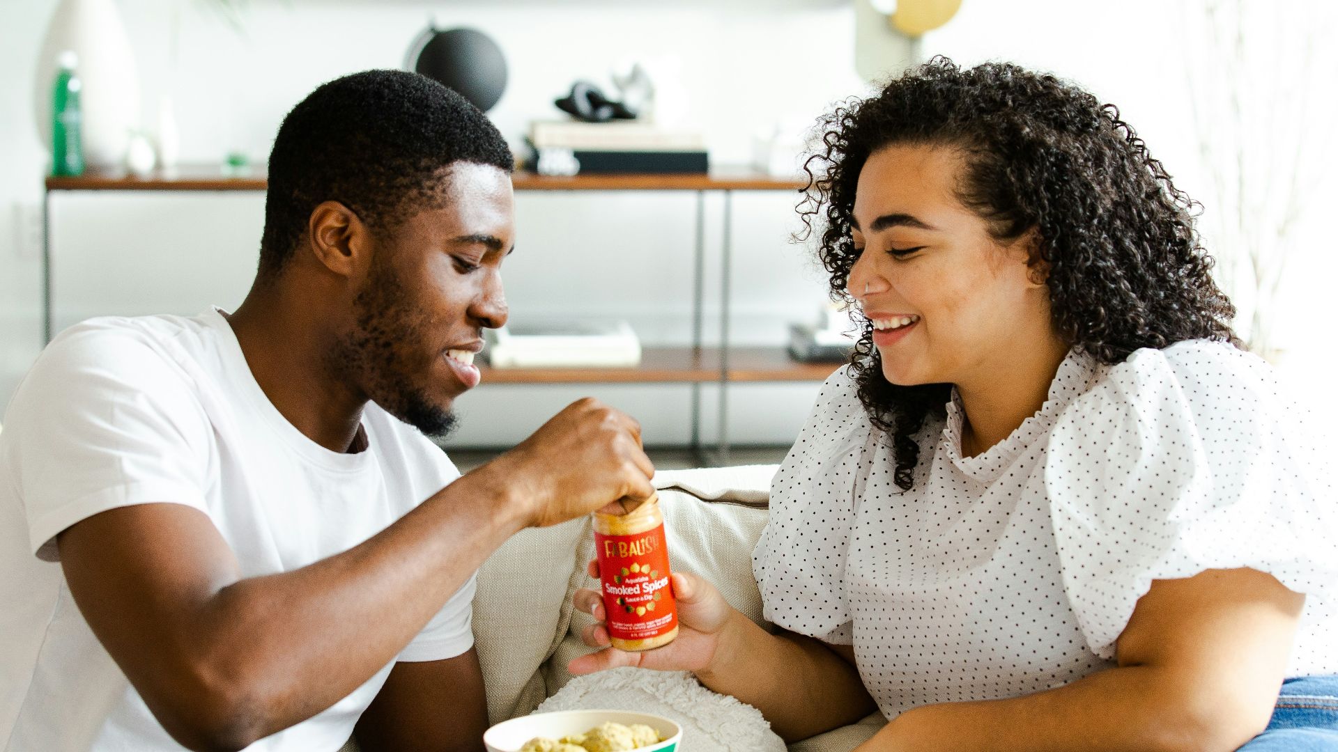 man in white crew neck t-shirt and blue denim jeans sitting on white sofa chair