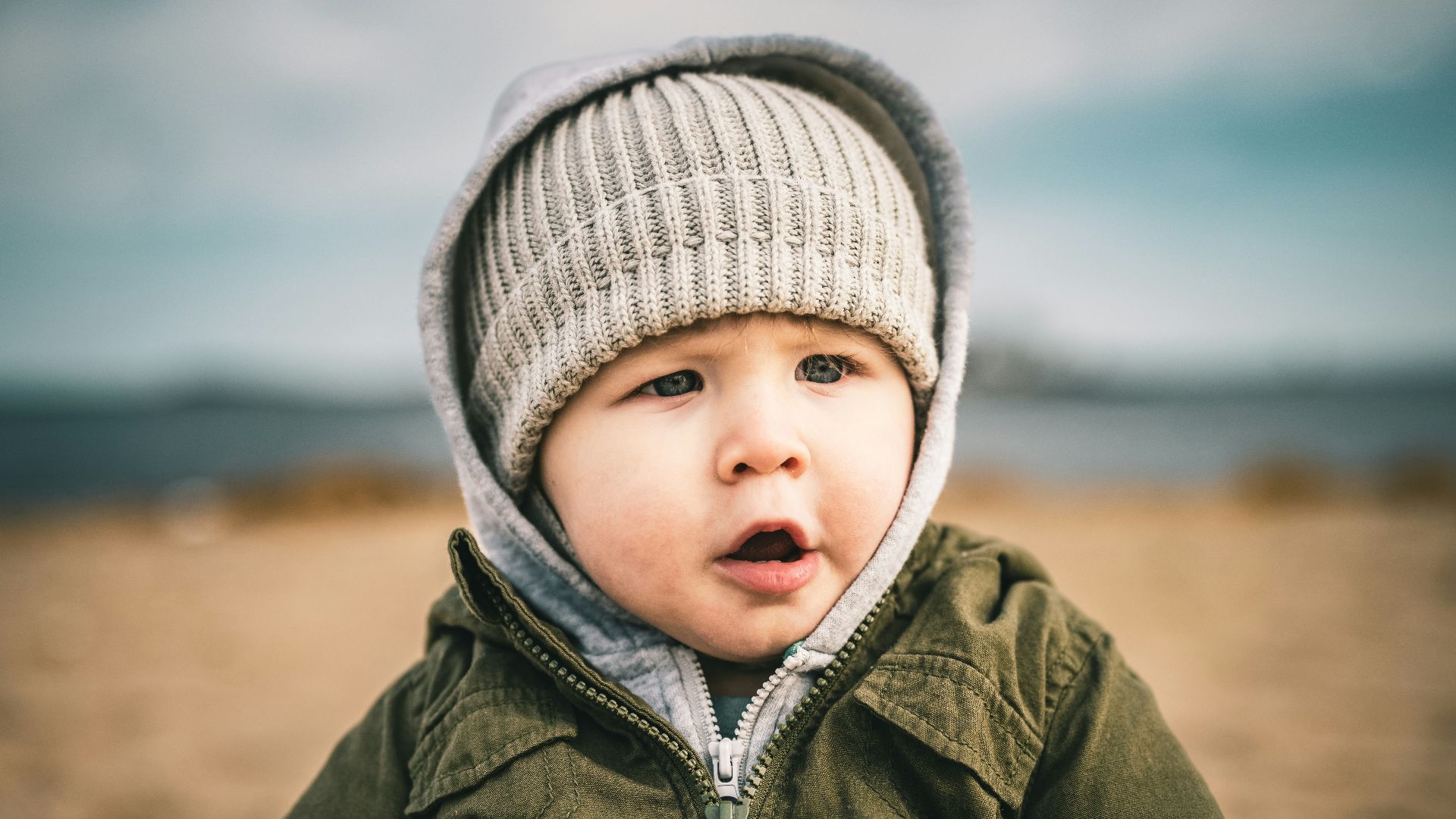 a small child wearing a hat and holding a rock