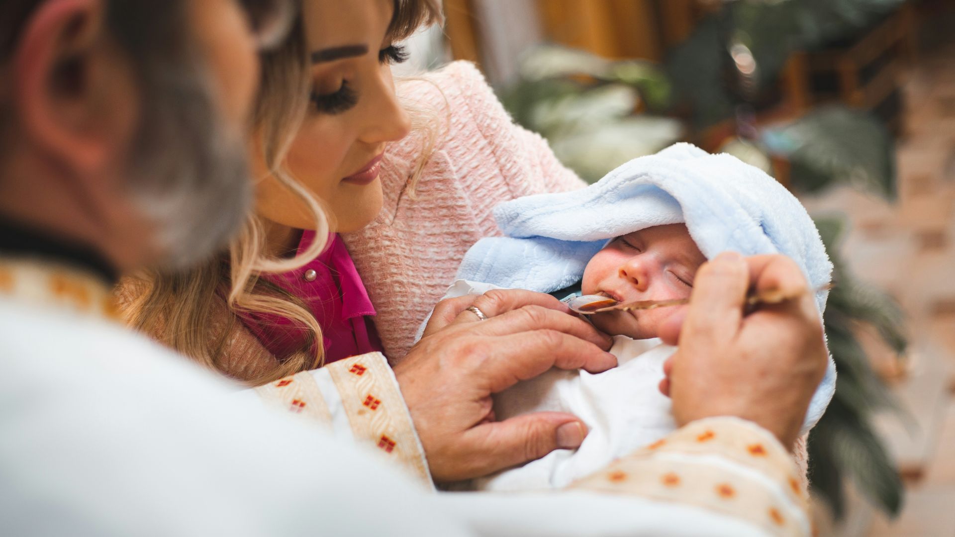 Priest anoints baby during a baptism ceremony.