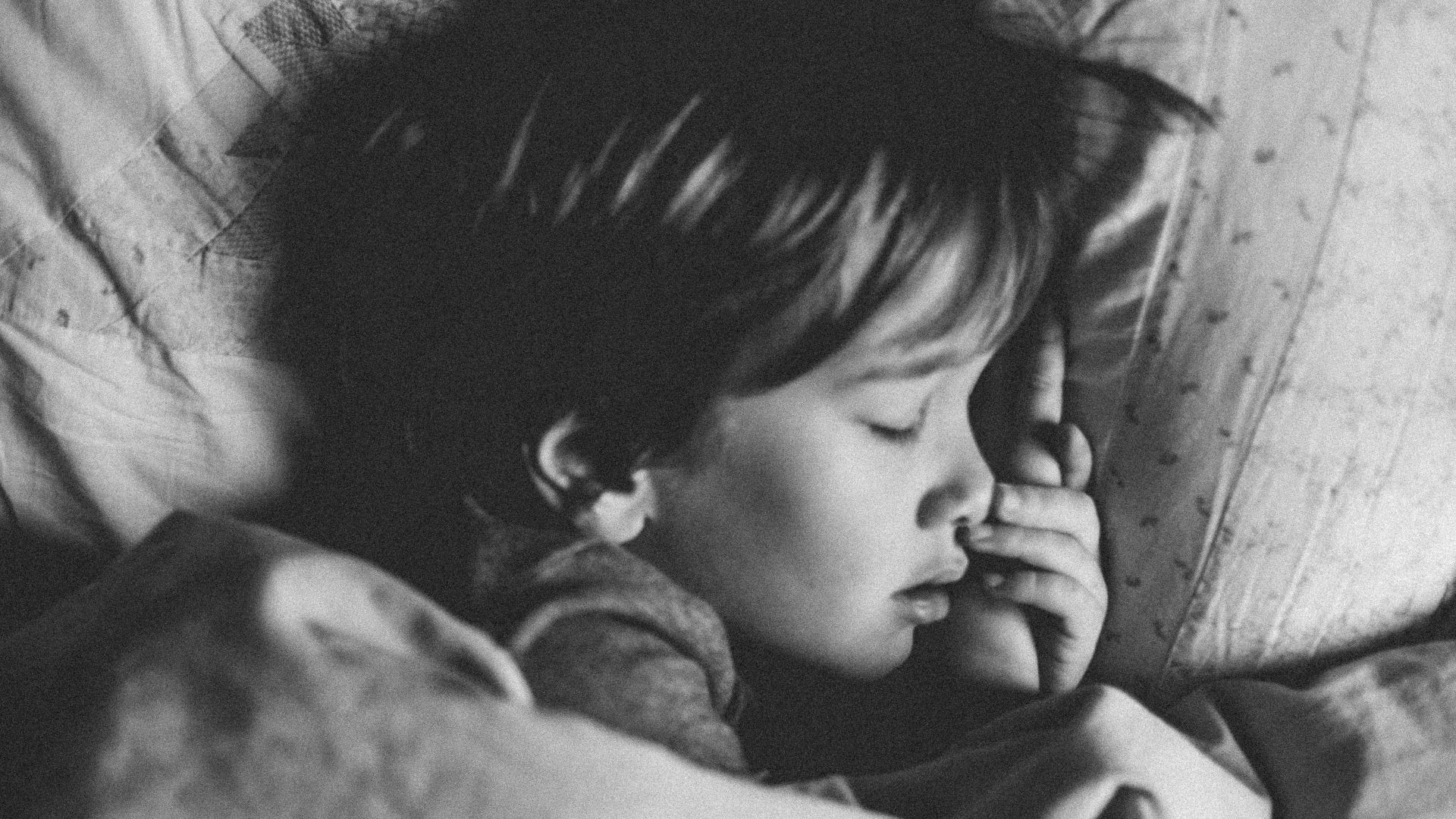 grayscale photo of girl sleeping on white pillow