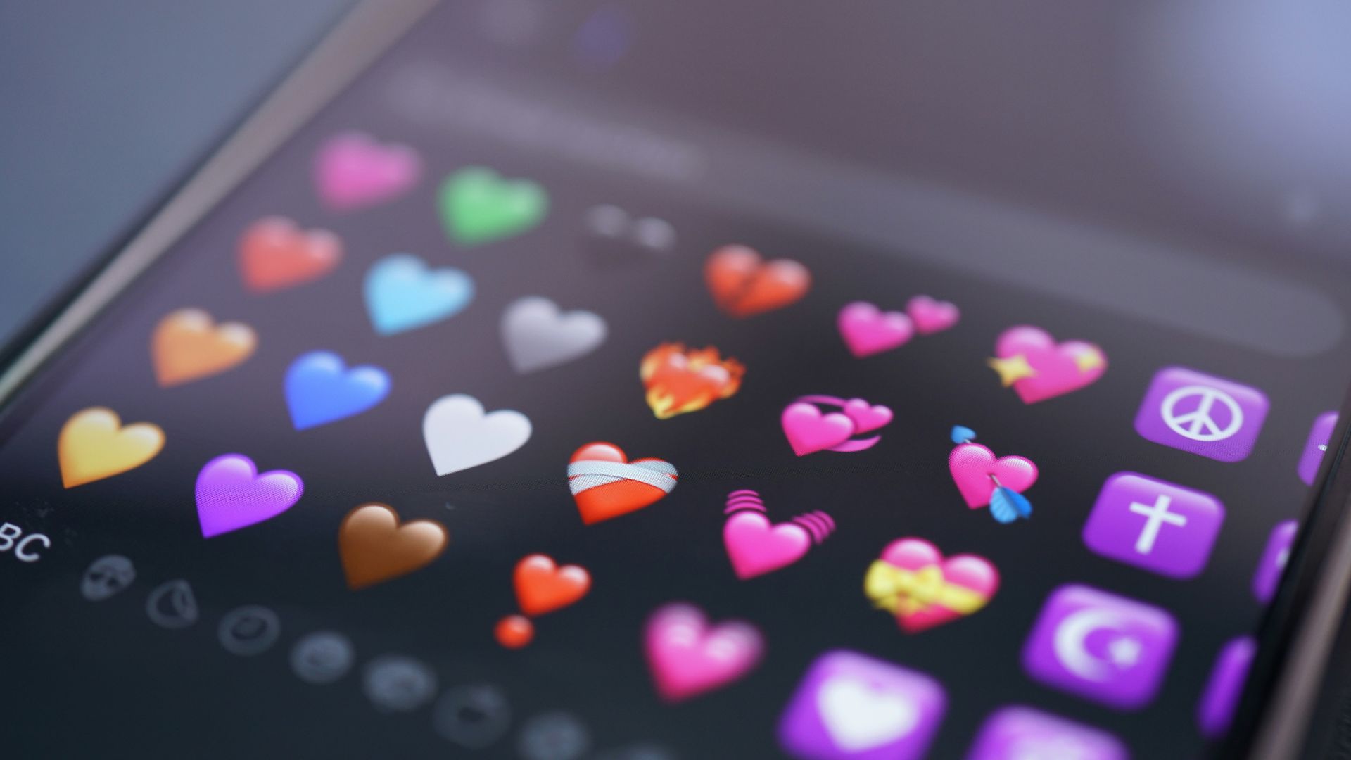 A phone screen displays colorful heart emojis.