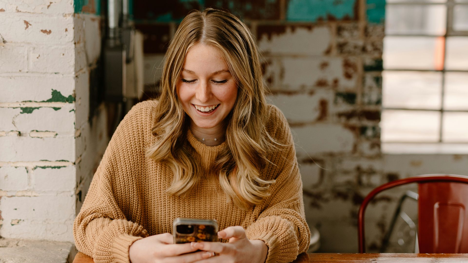 a woman sitting at a table looking at her cell phone