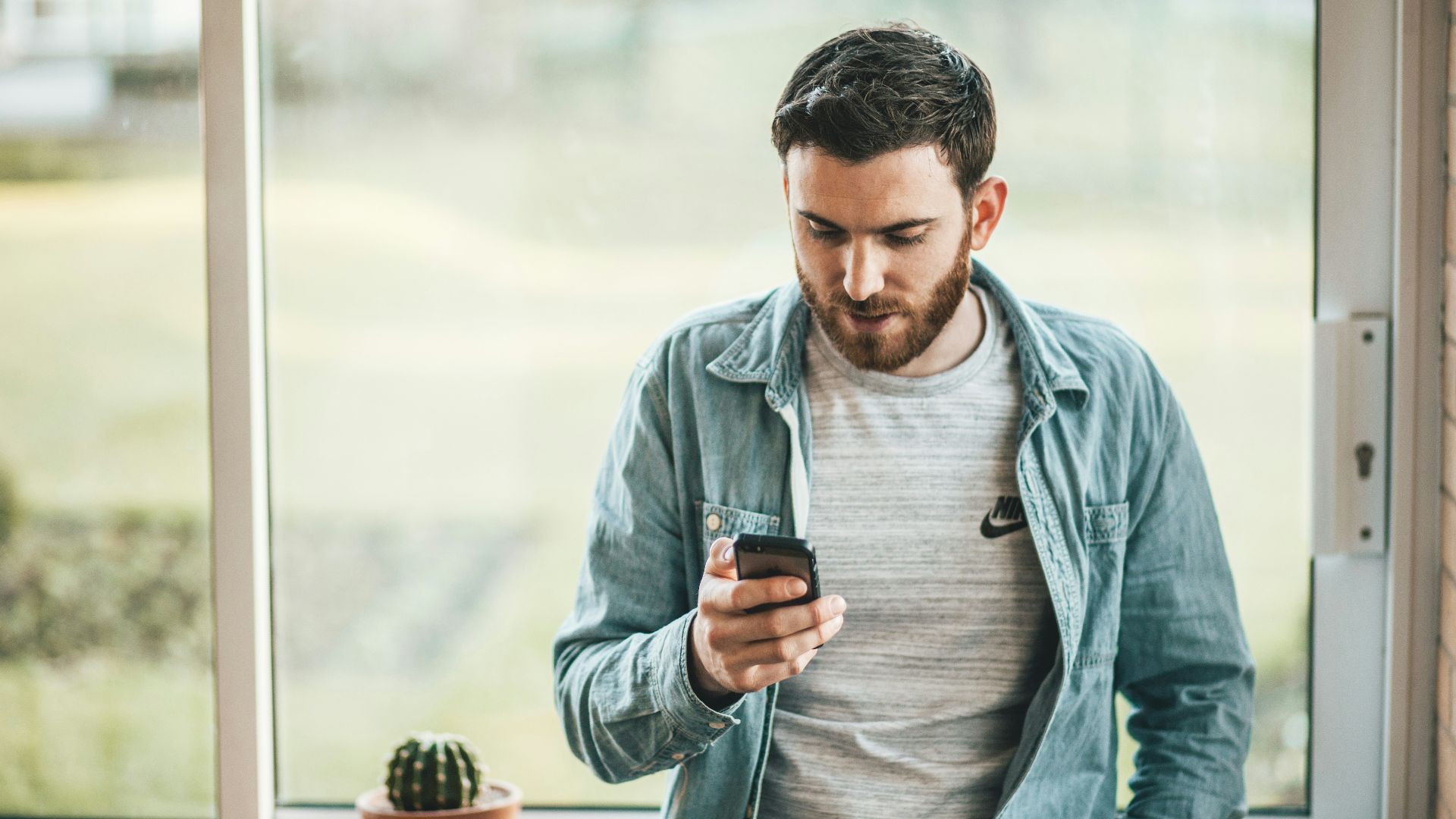 man holding a smartphone near the window